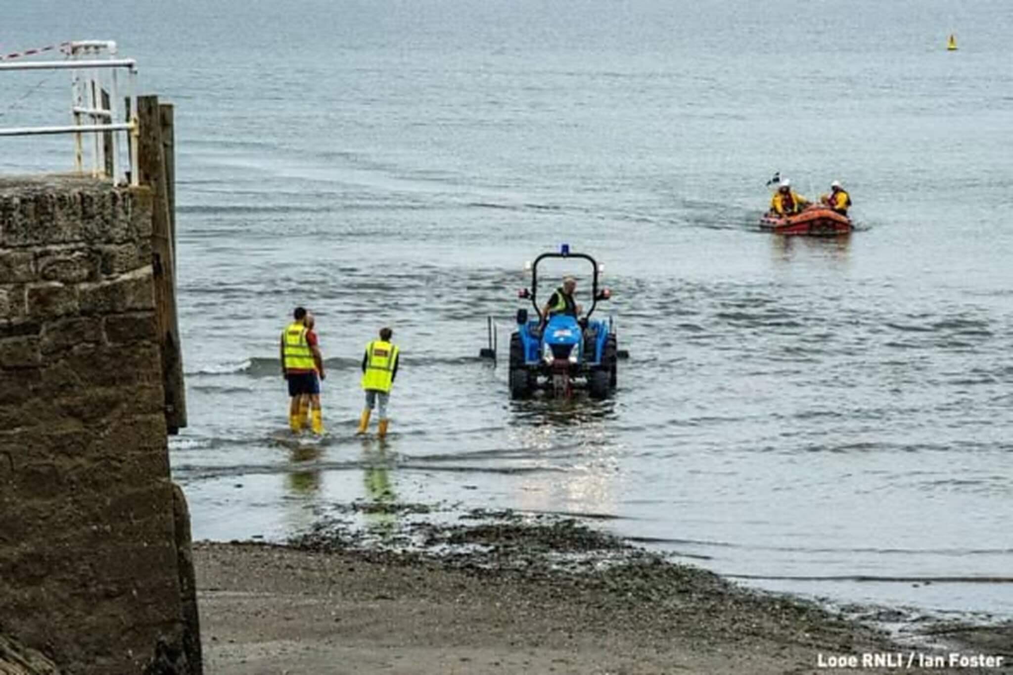 Tractor towing Looe RNLI's D Class lifeboat into the water at low tide