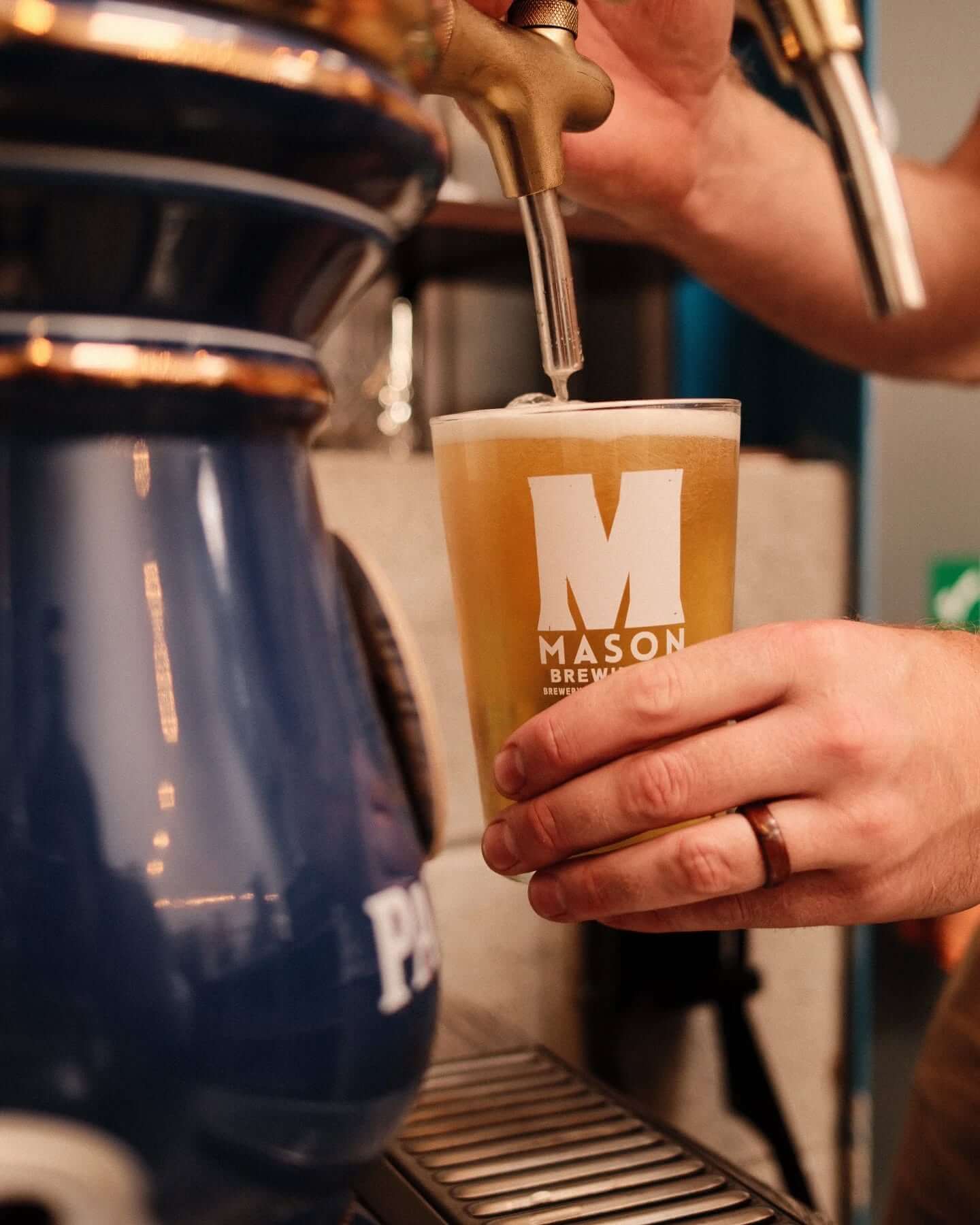 A pint being poured into a Mason Brewing Co glass at the taproom bar