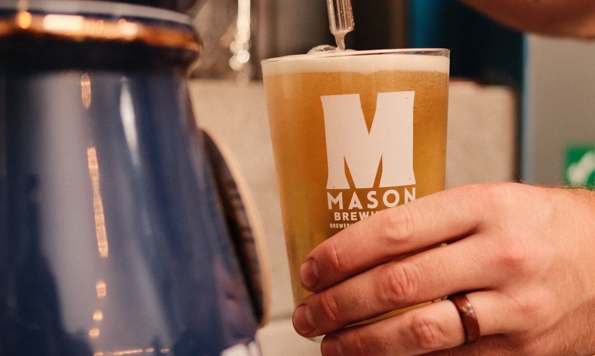 A pint being poured into a Mason Brewing Co glass at the taproom bar
