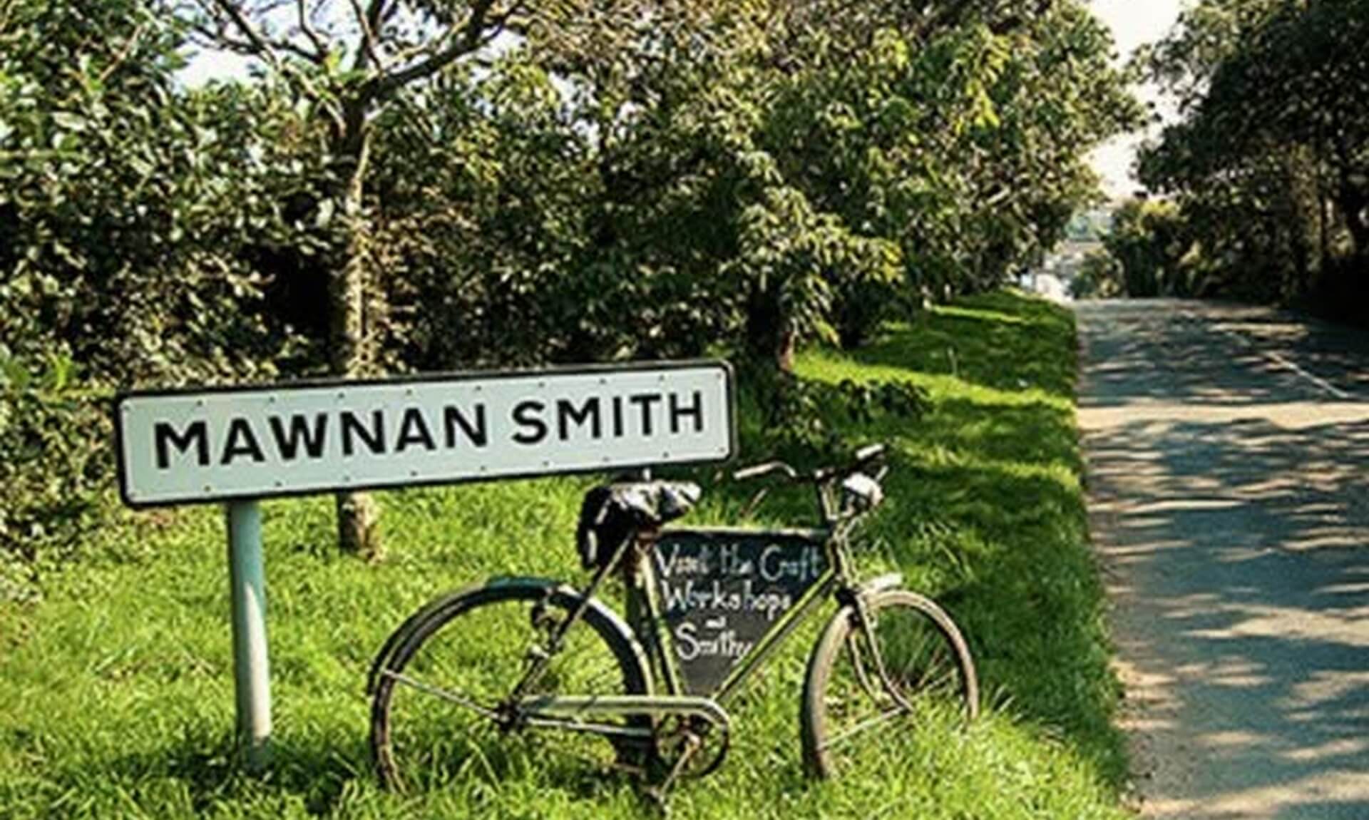 The Mawnan Smith village sign beside an old bicycle on a Cornish lane