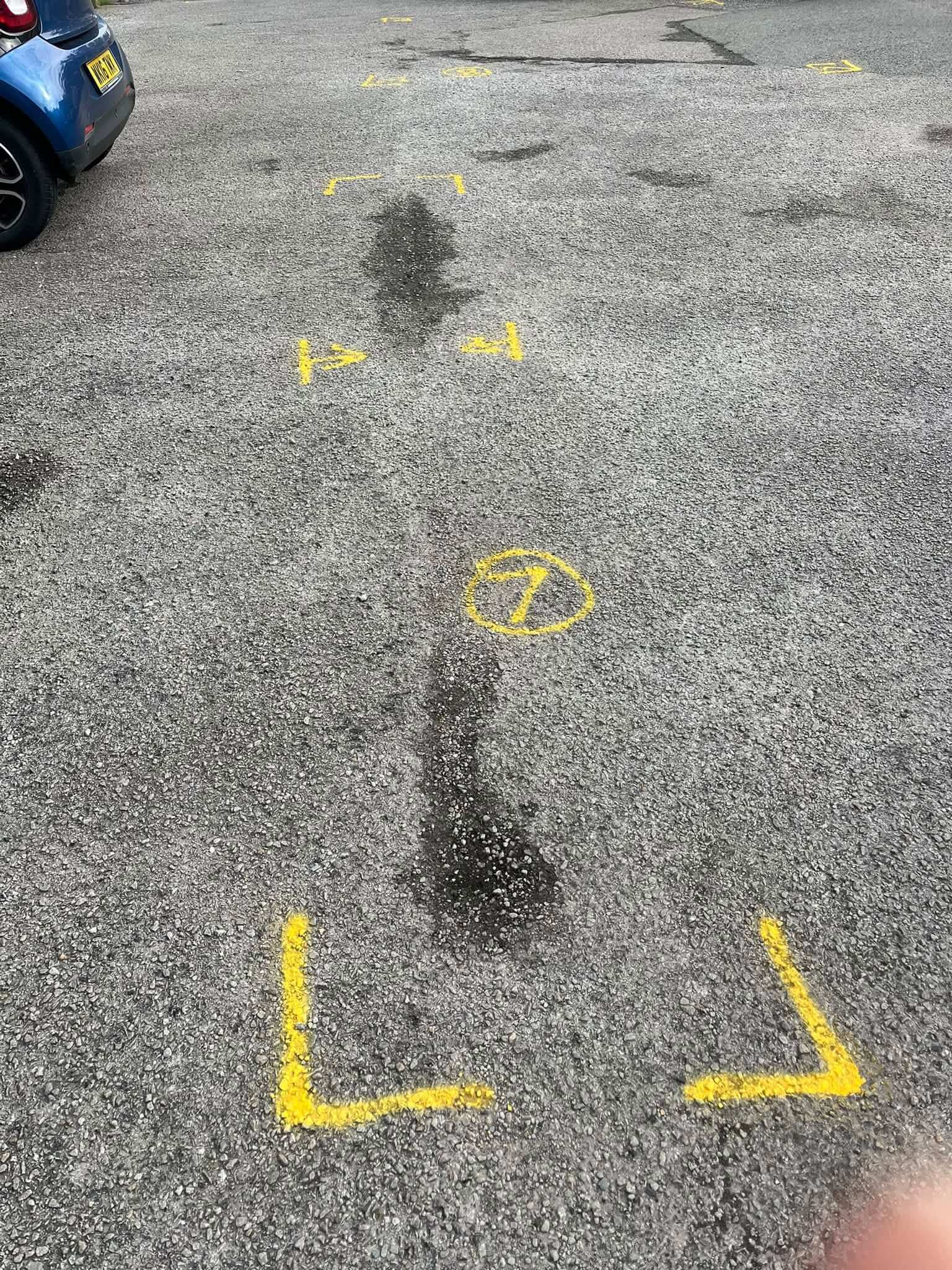 Yellow paint marking out patches of tarmac to be resurfaced at a Millbrook car park