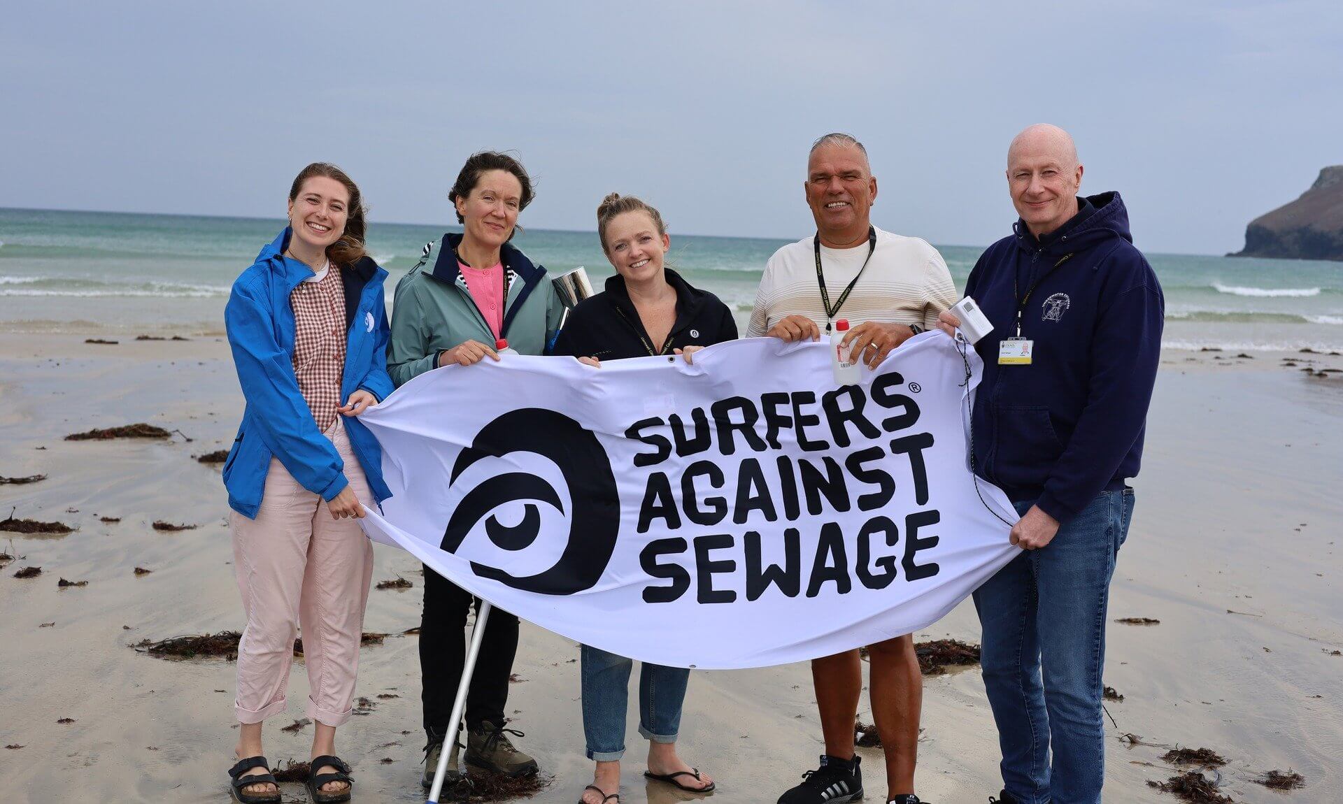 Councillors on the beach holding a Surfers Against Sewage banner