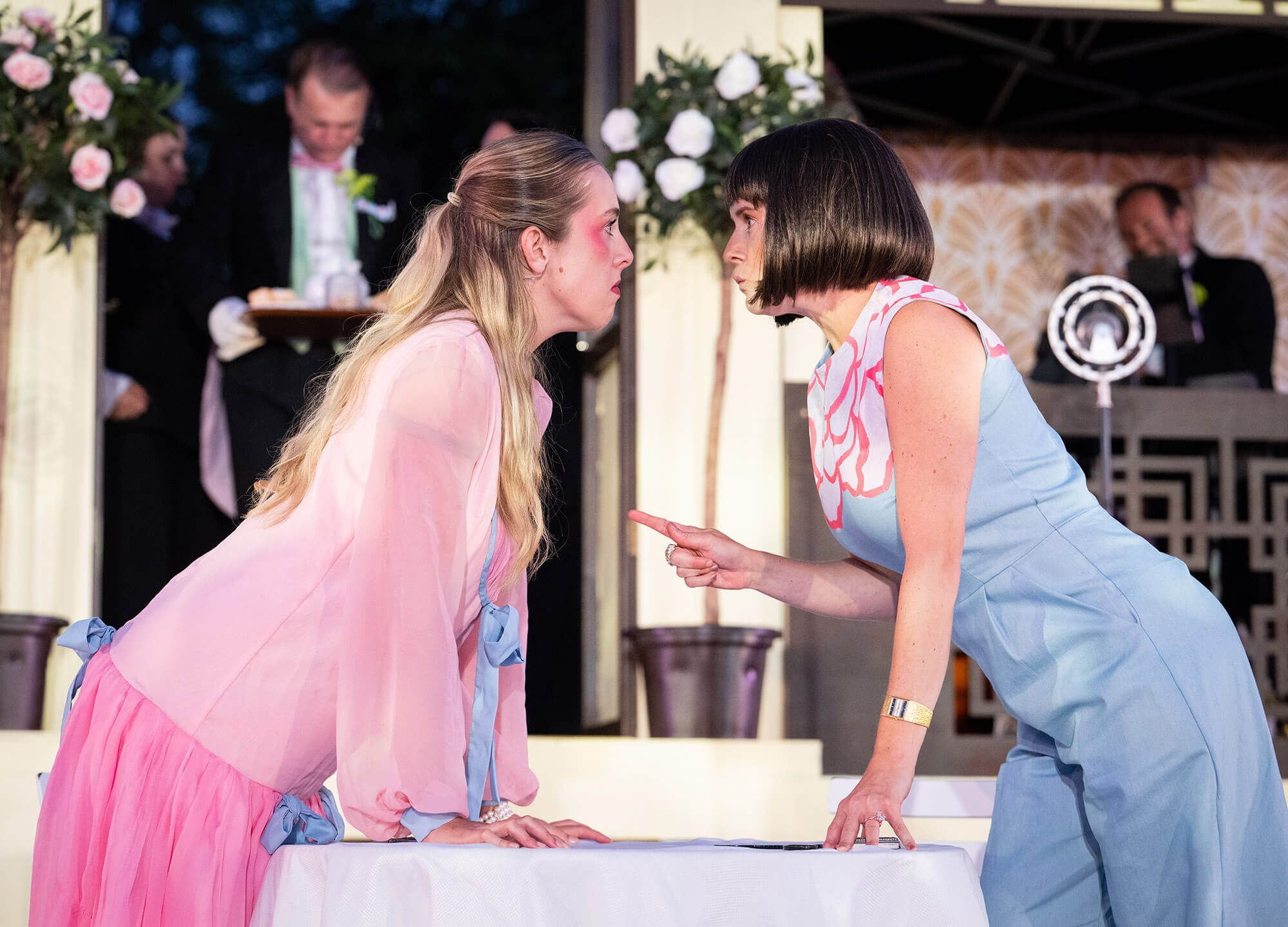 Two female cast members in a tense exchange on stage