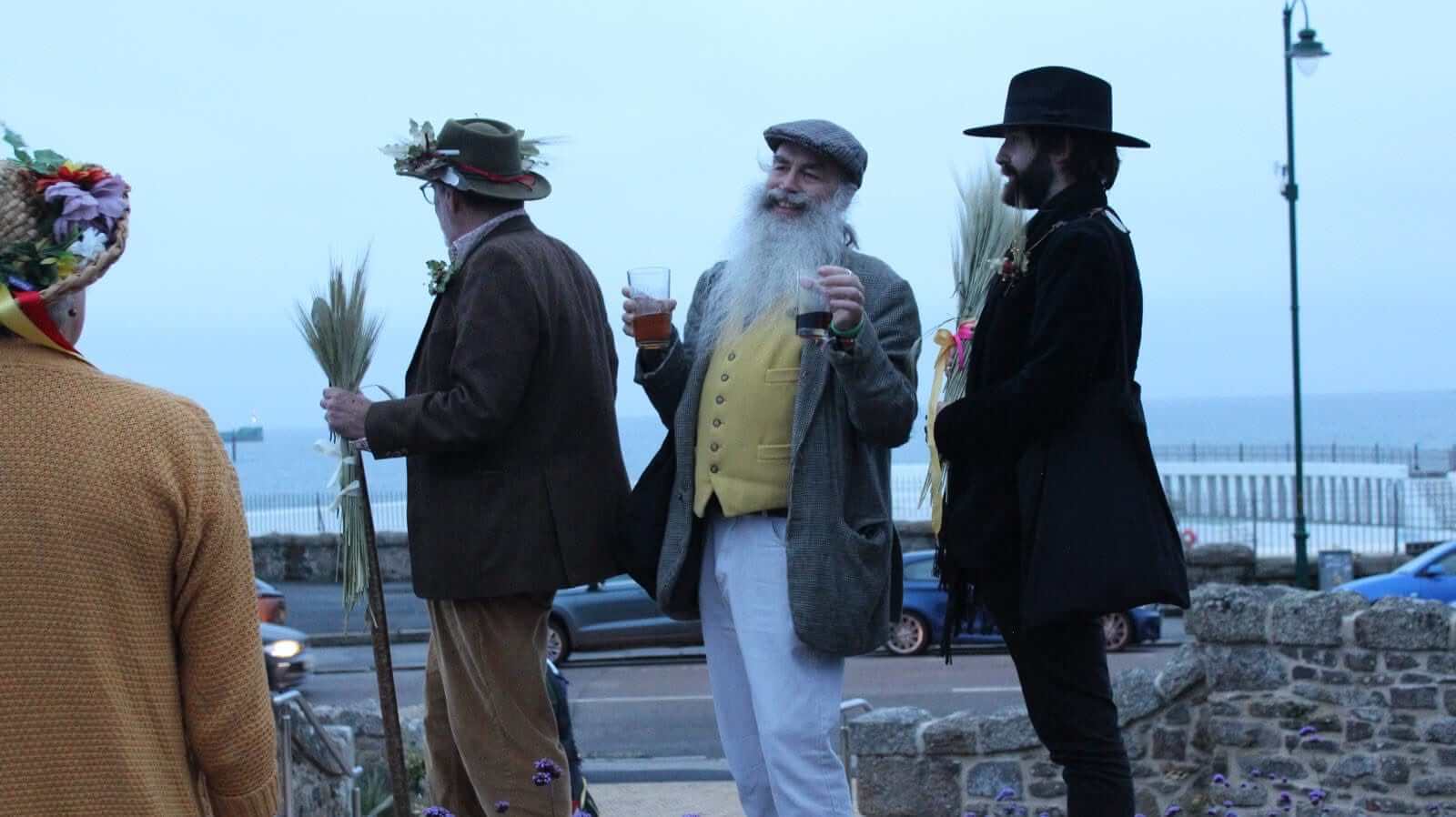 Guldize revellers with corn sheaves overlooking Mount's Bay in Penzance