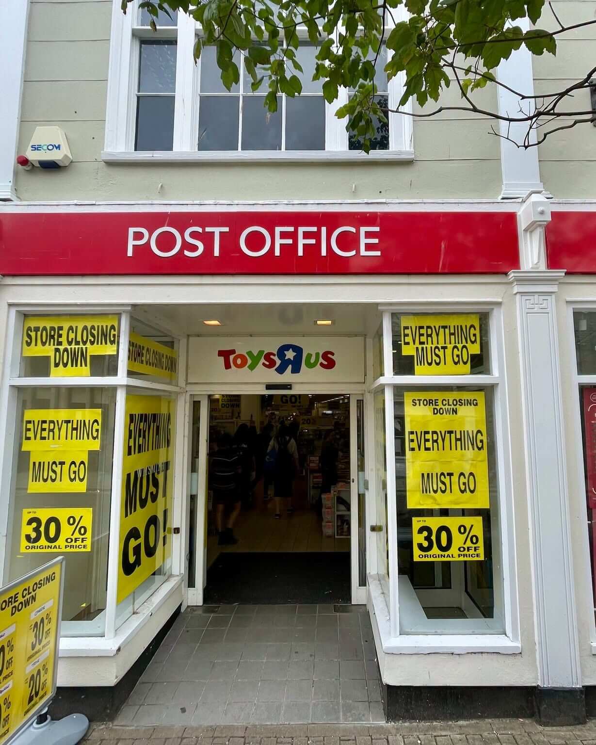Post Office signage above a shop with closing down sale signs in the windows