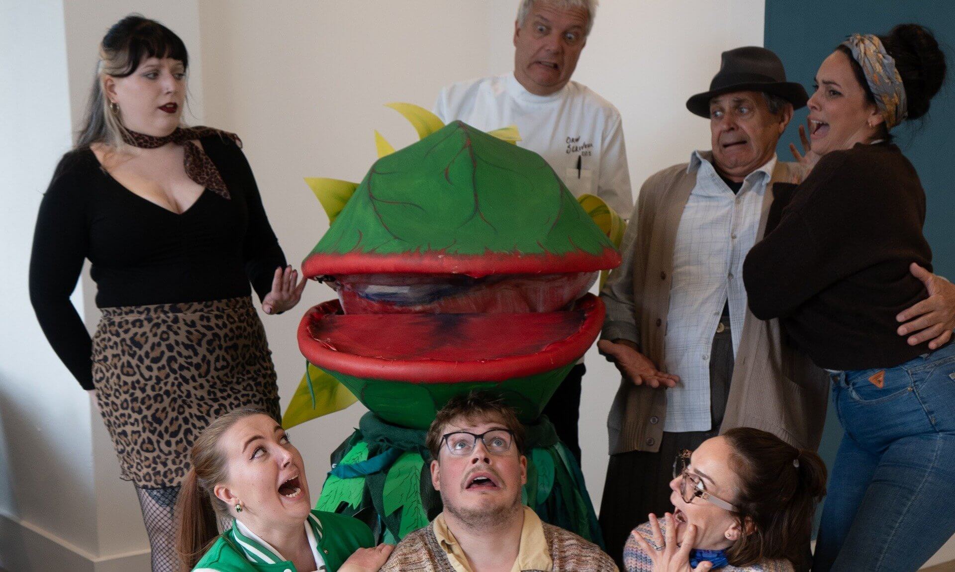 Teylu Theatre Company cast recoiling in mock horror around the Audrey II plant puppet