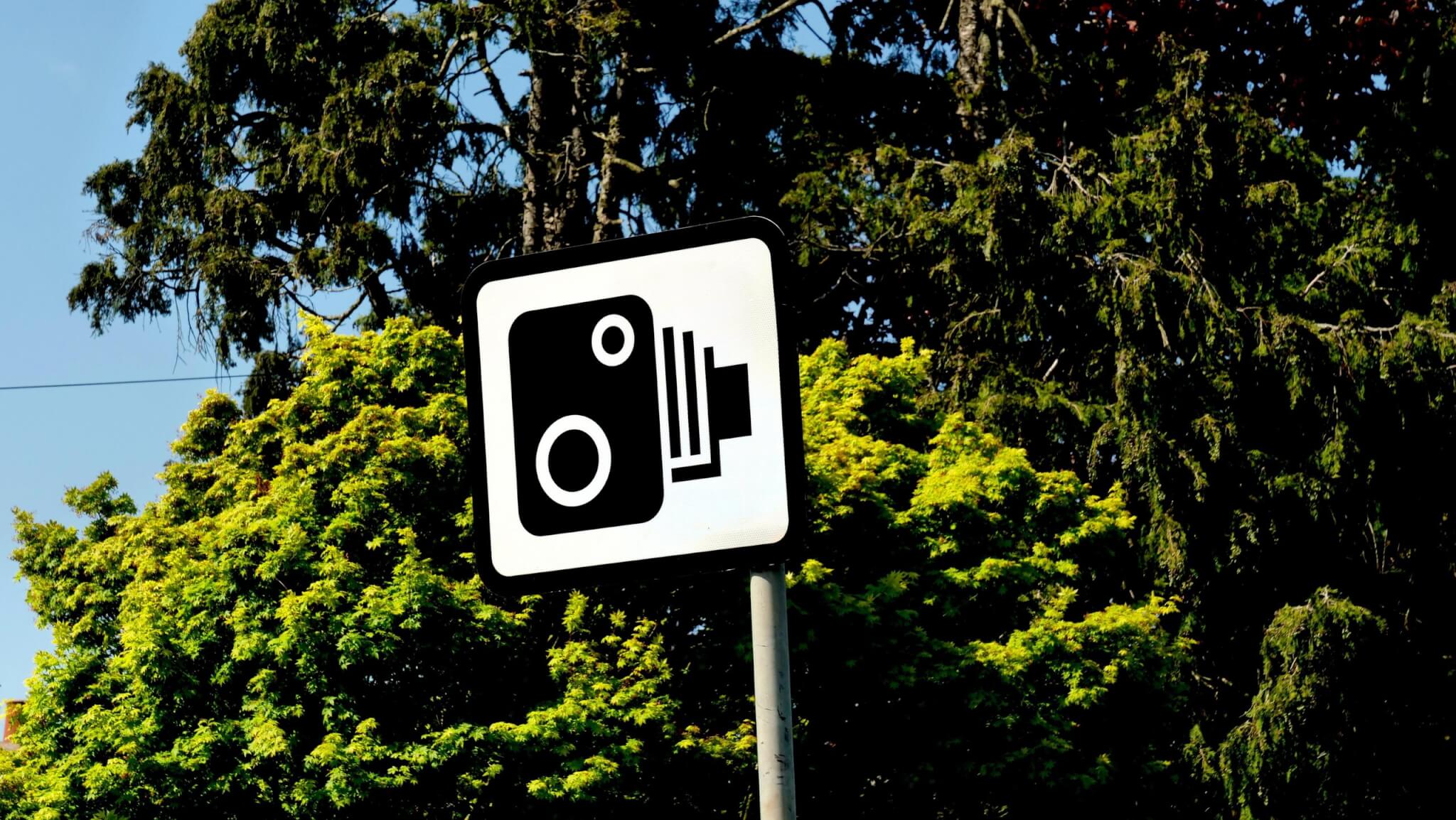 Speed camera warning sign in front of trees