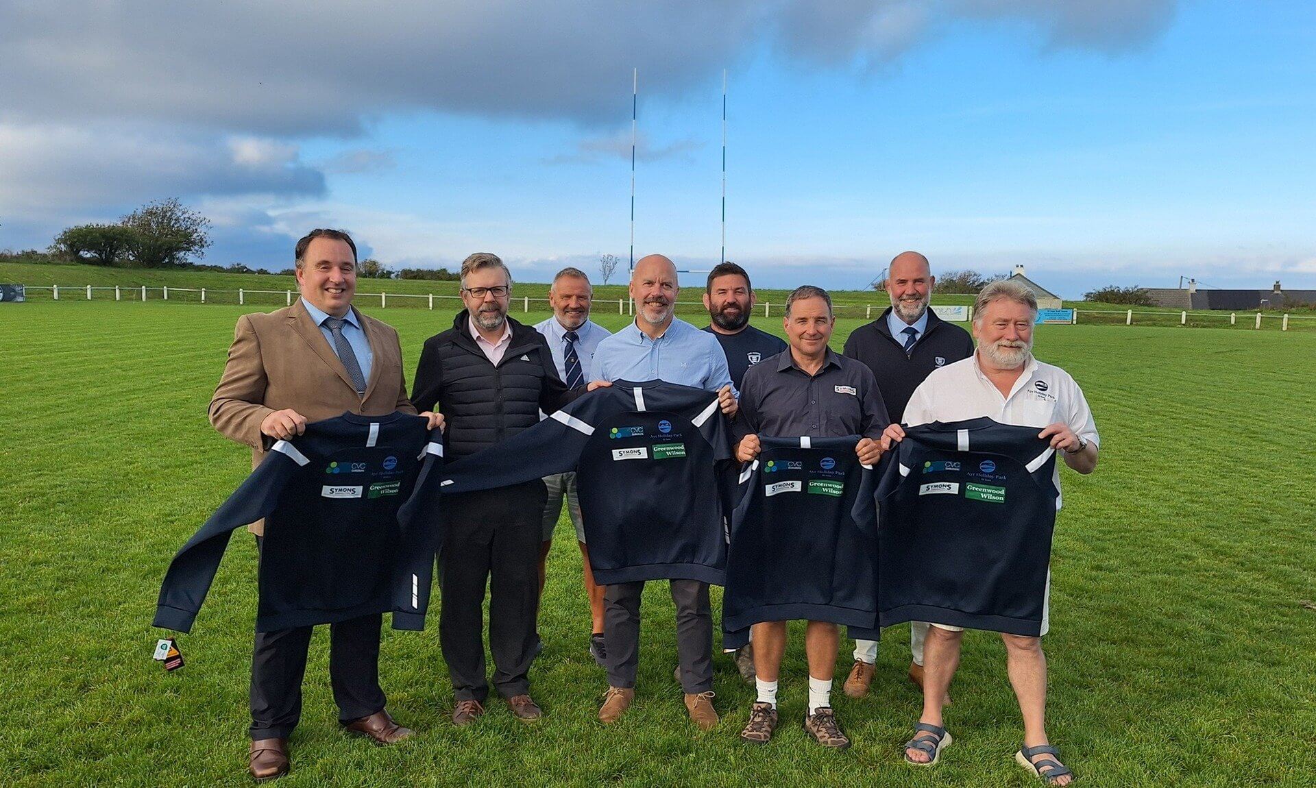 St Ives RFC and sponsors holding the new off-field kit on the pitch in front of the rugby posts