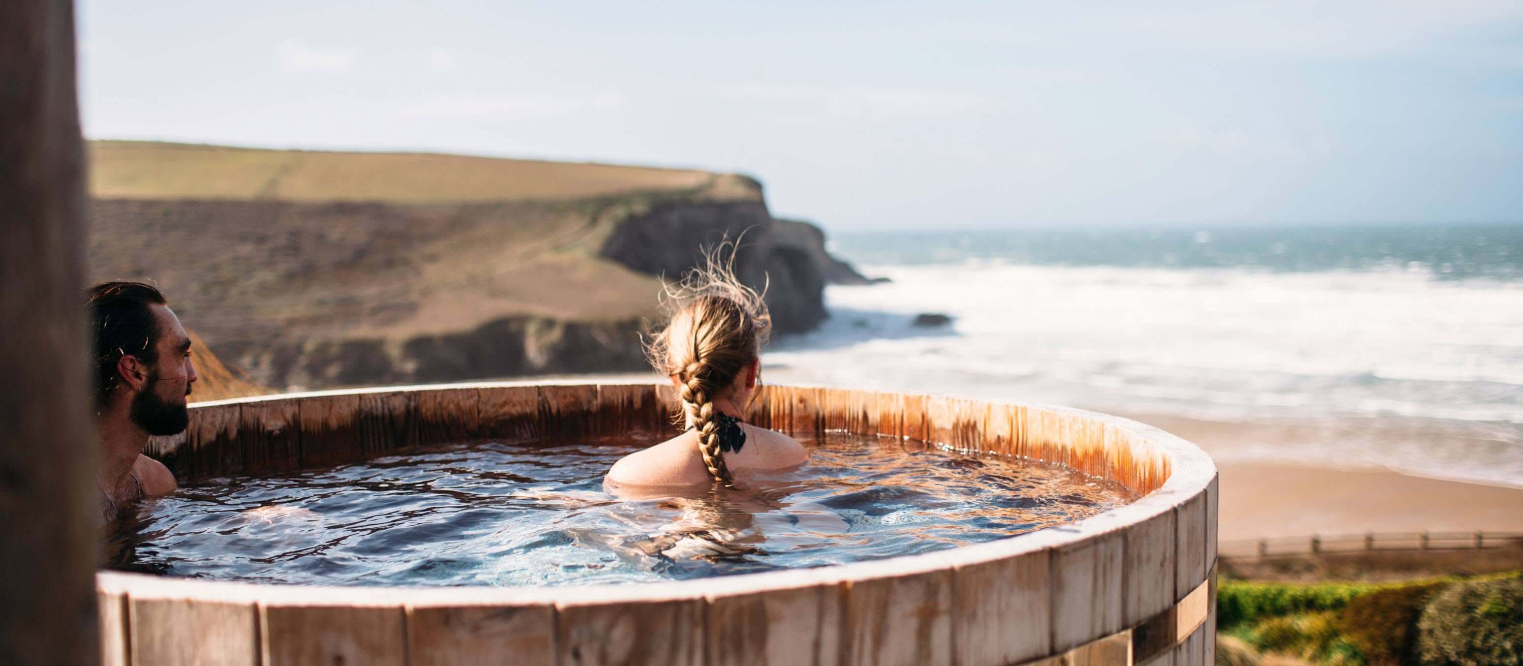 Guests in a clifftop hot tub at The Scarlet Hotel, Mawgan Porth
