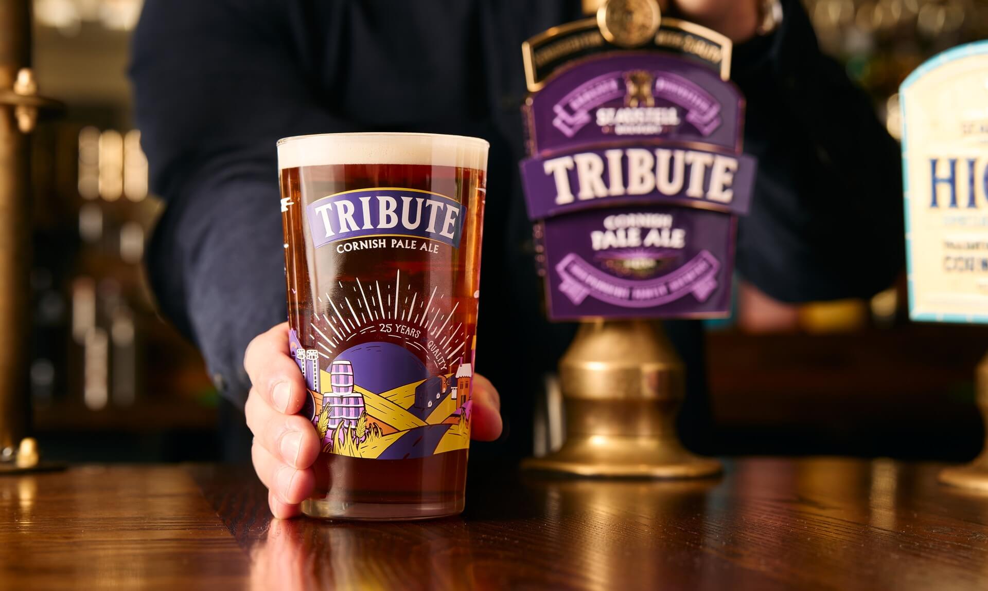 A pint of Tribute Cornish Pale Ale on a pub bar next to the Tribute pump clip