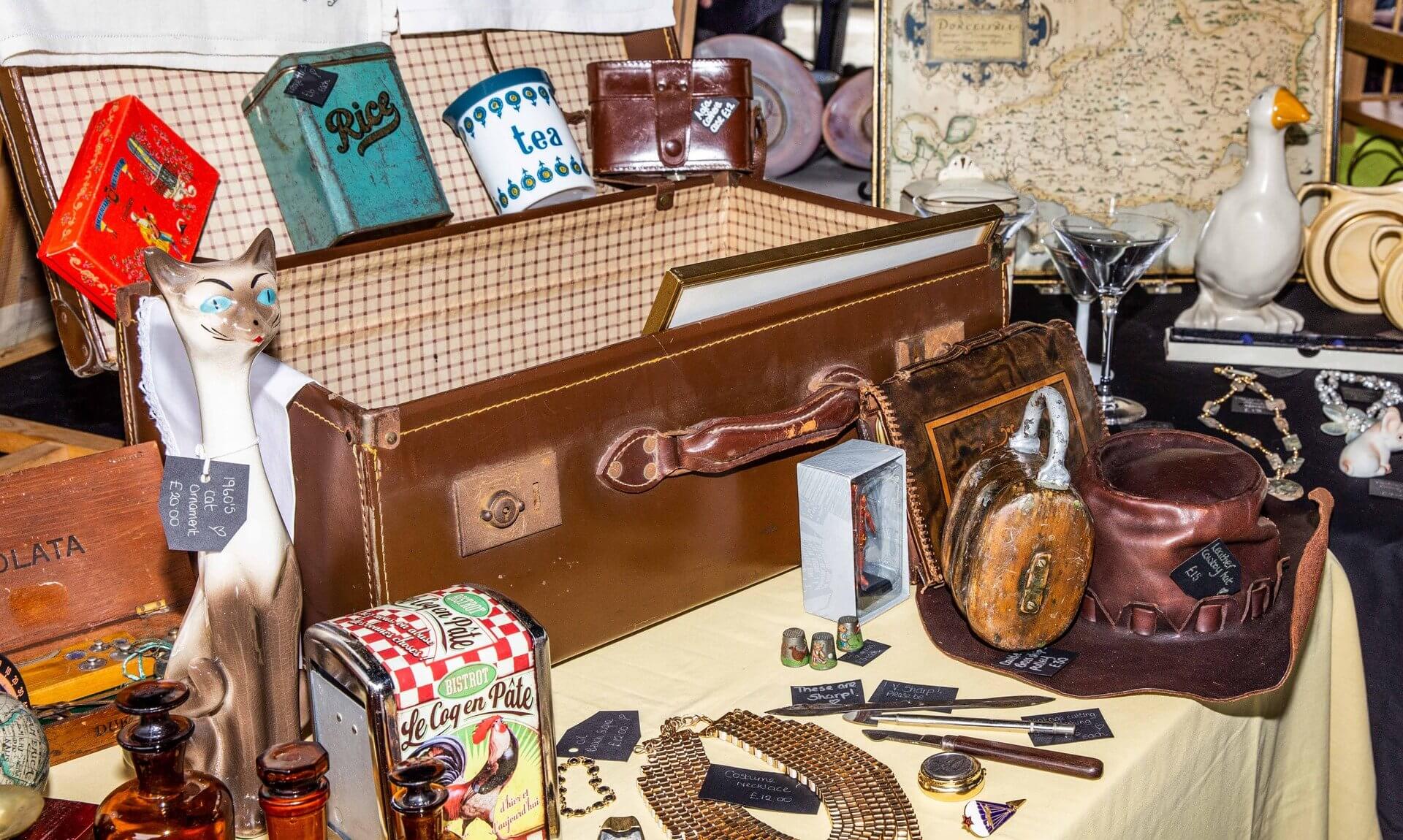 Vintage suitcase, tins, a 1960s cat ornament and collectables on a stall at a previous Truro Antiques and Collectables Market