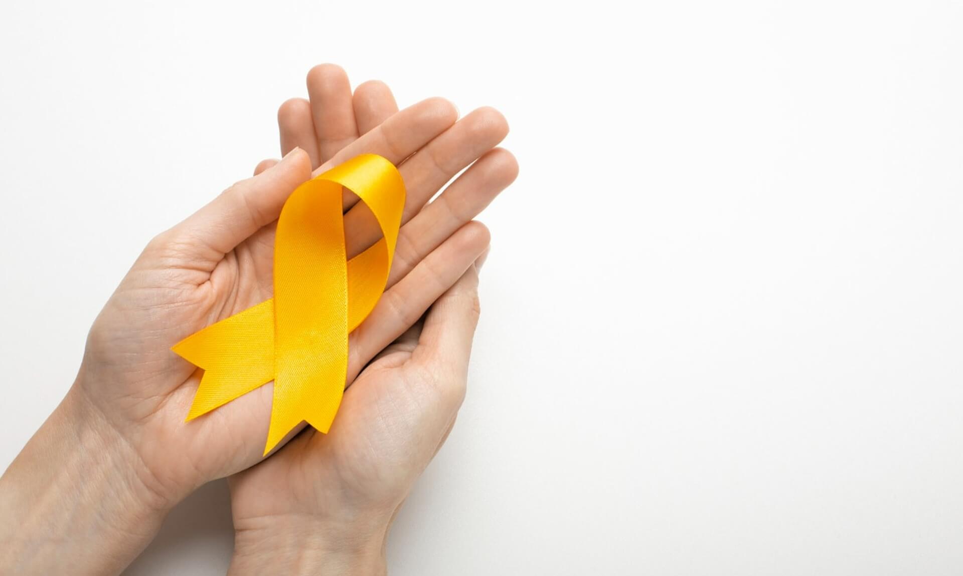 Two open hands cupping a yellow ribbon, the suicide prevention awareness symbol