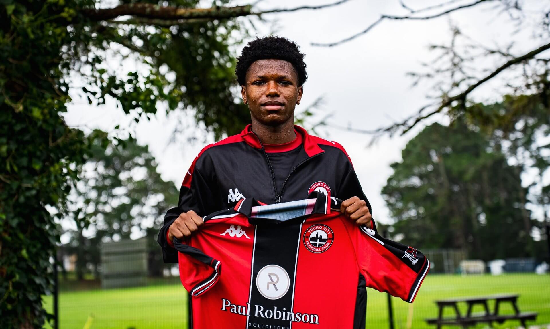Zyan Blake holding up a Truro City home shirt