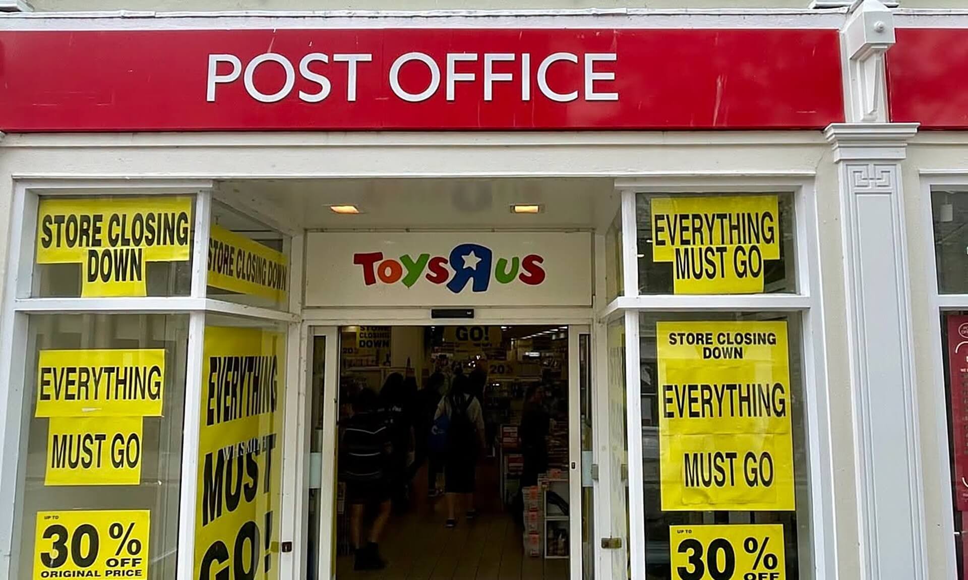 Post Office signage above a shop with closing down sale signs in the windows