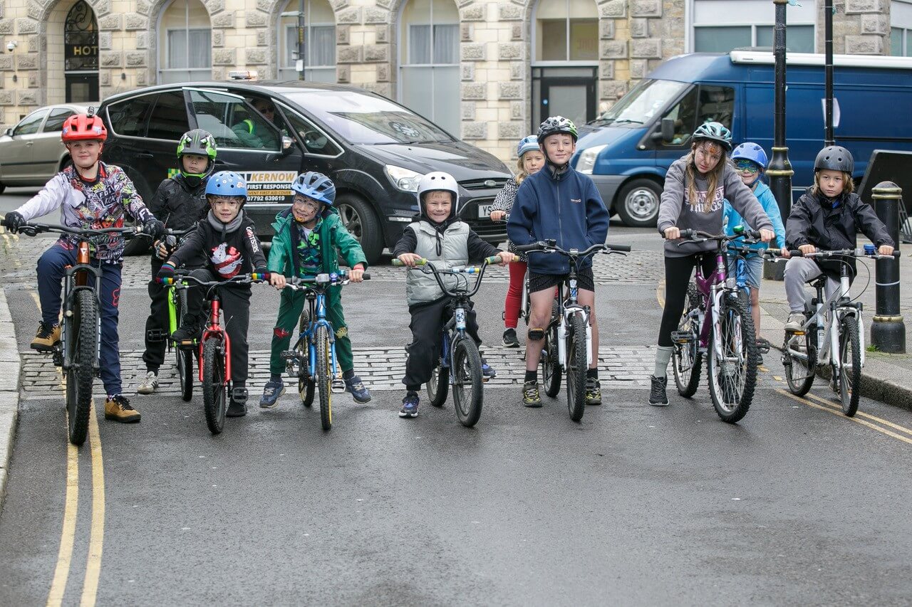 Children lined up on bikes and BMXs on a Camborne street for Tykes on Trikes