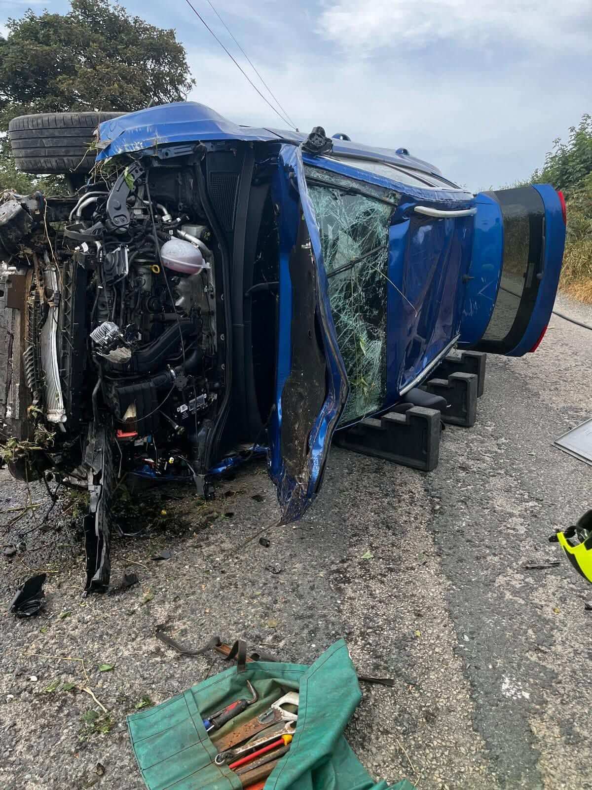 Extrication tools laid out beside a crashed car