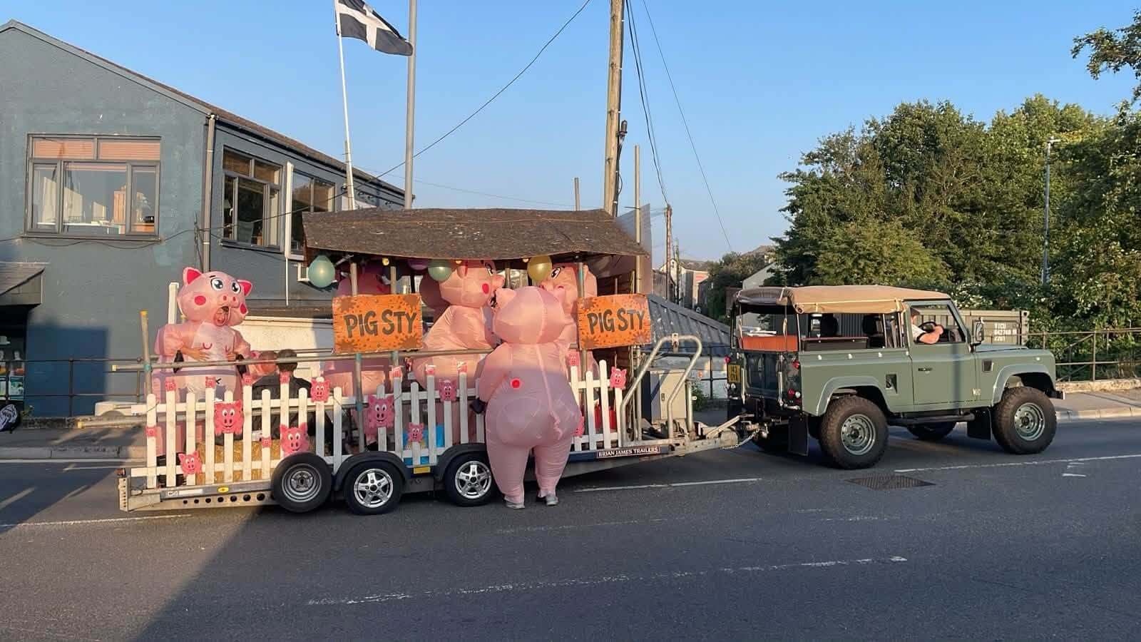 Inflatable pig sty carnival float on a Wadebridge street
