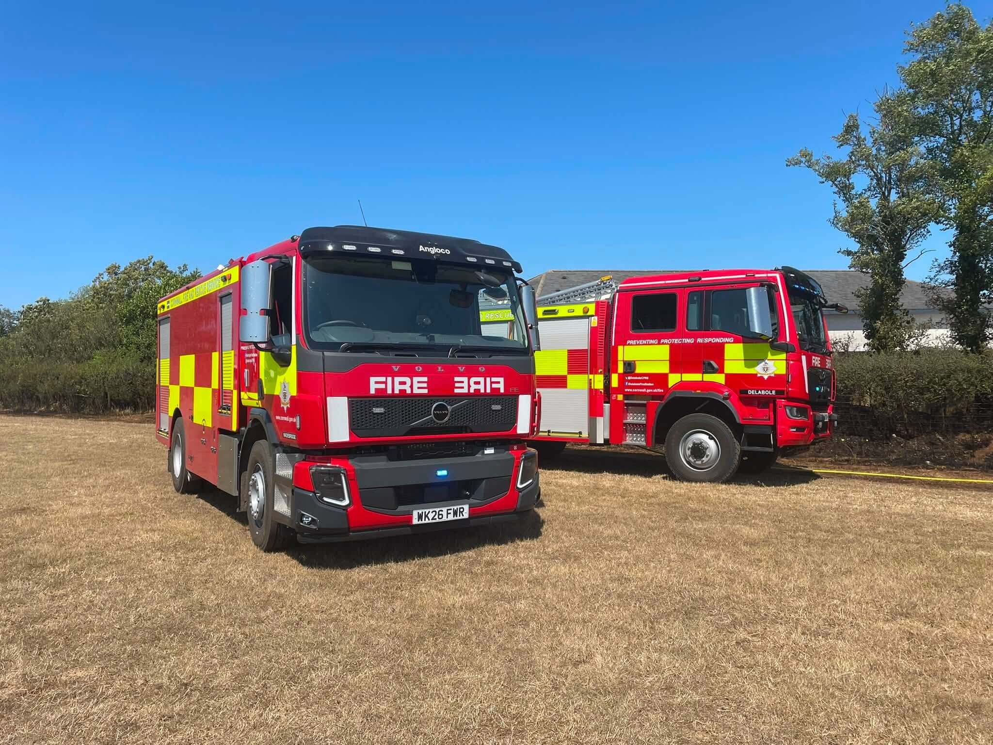 Fire engines parked on parched grass during a dry summer