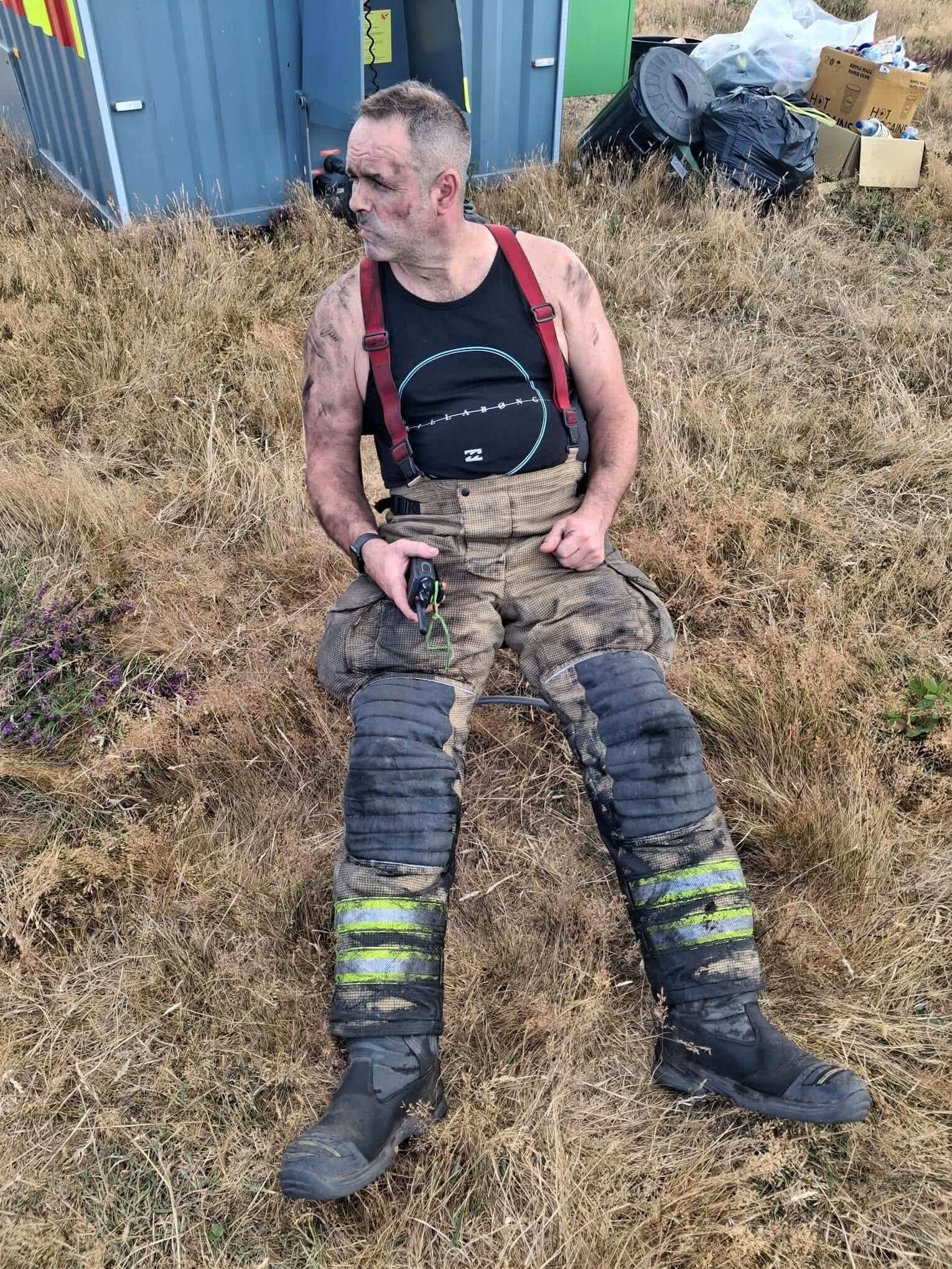 Exhausted firefighter sitting down after tackling a wildfire