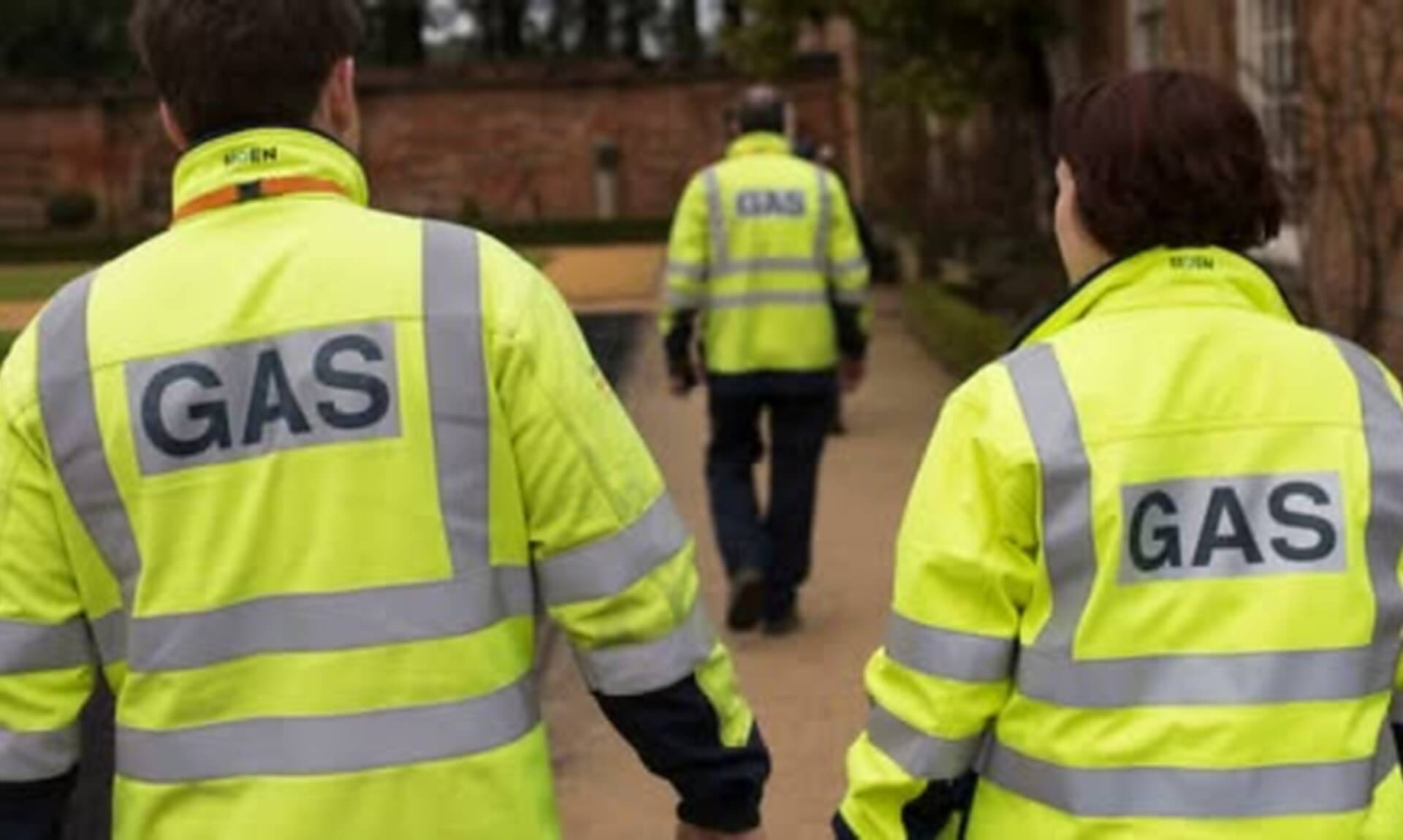 Gas engineers walking away from camera wearing hi-vis GAS jackets