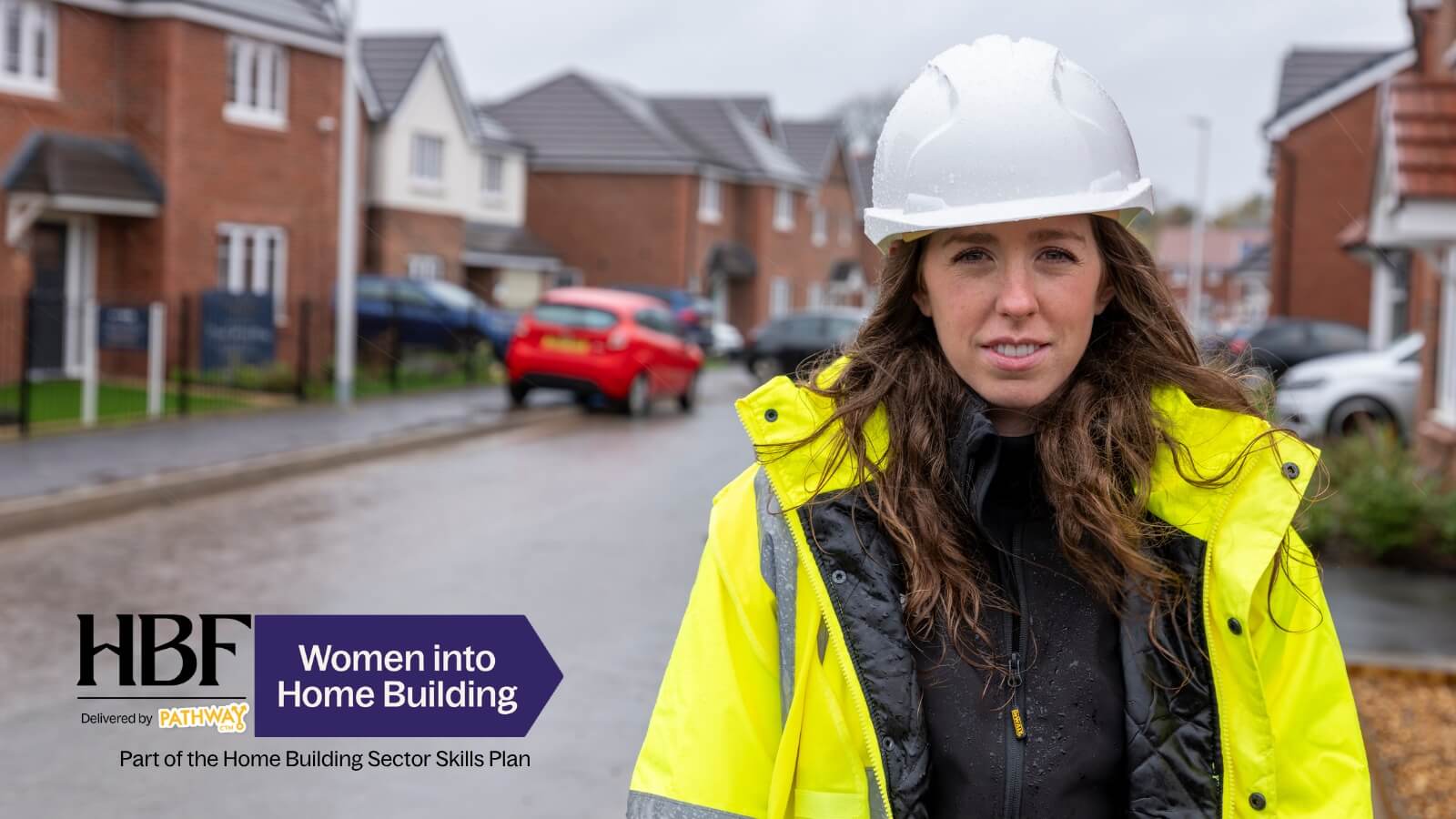 A woman in a hard hat and hi-vis practising a trade task in a kitchen