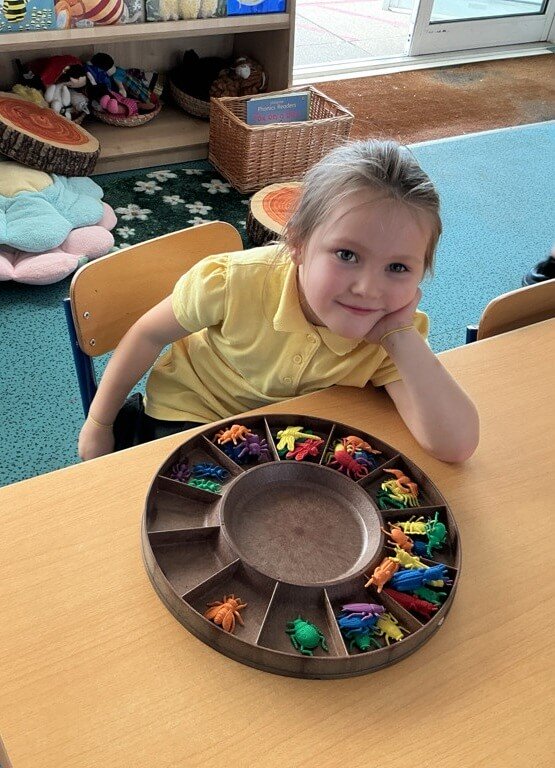 Grace at her classroom table with a bug sorting tray