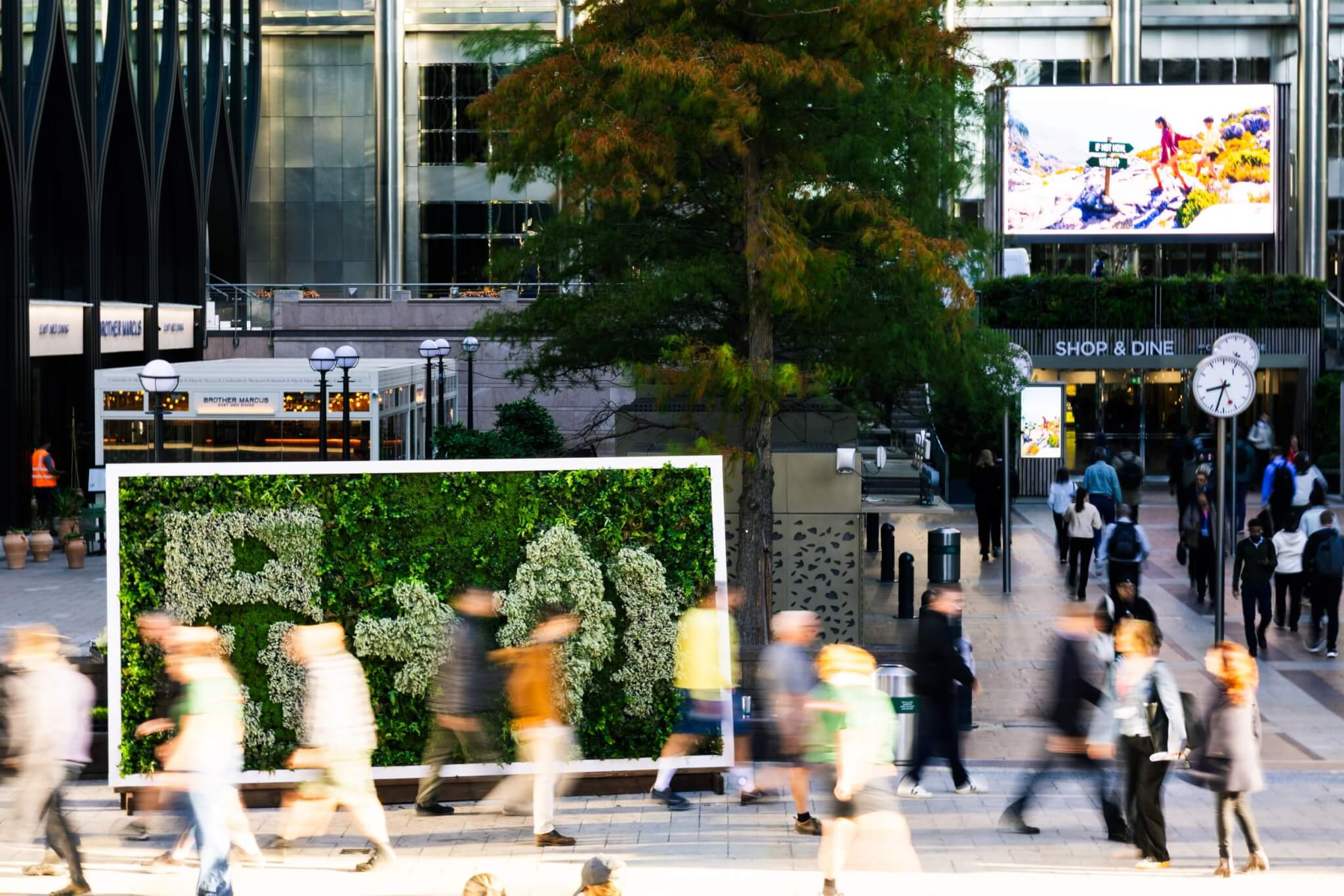 Commuters walk past the living Emergency Exit sign in Canary Wharf