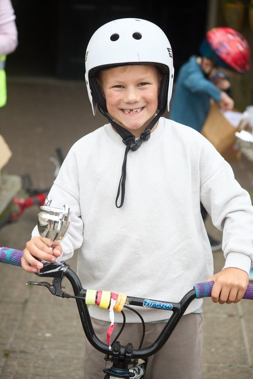 A boy on a BMX bike holding his Tykes on Trikes trophy