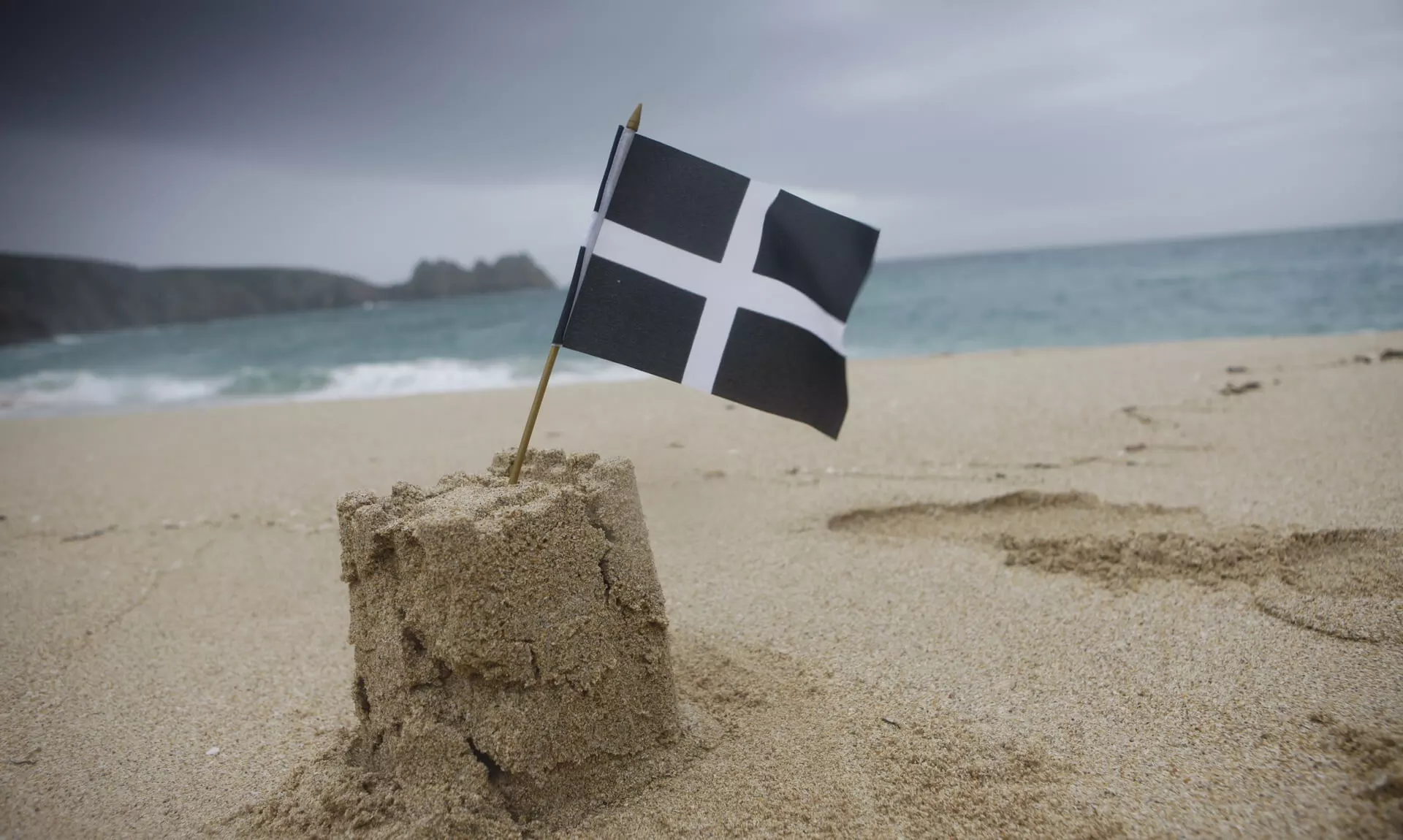 A St Piran's flag in a sandcastle on a Cornish beach
