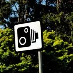 Speed camera warning sign in front of trees