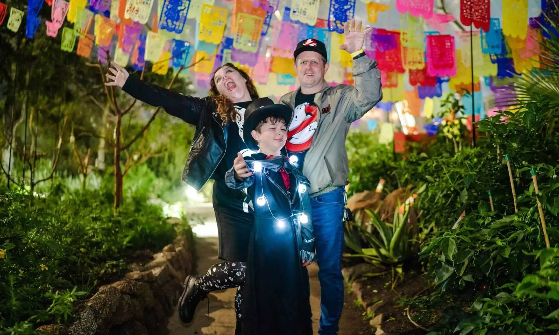 Family in Halloween costumes celebrating under colourful bunting at Eden Project Halloweden