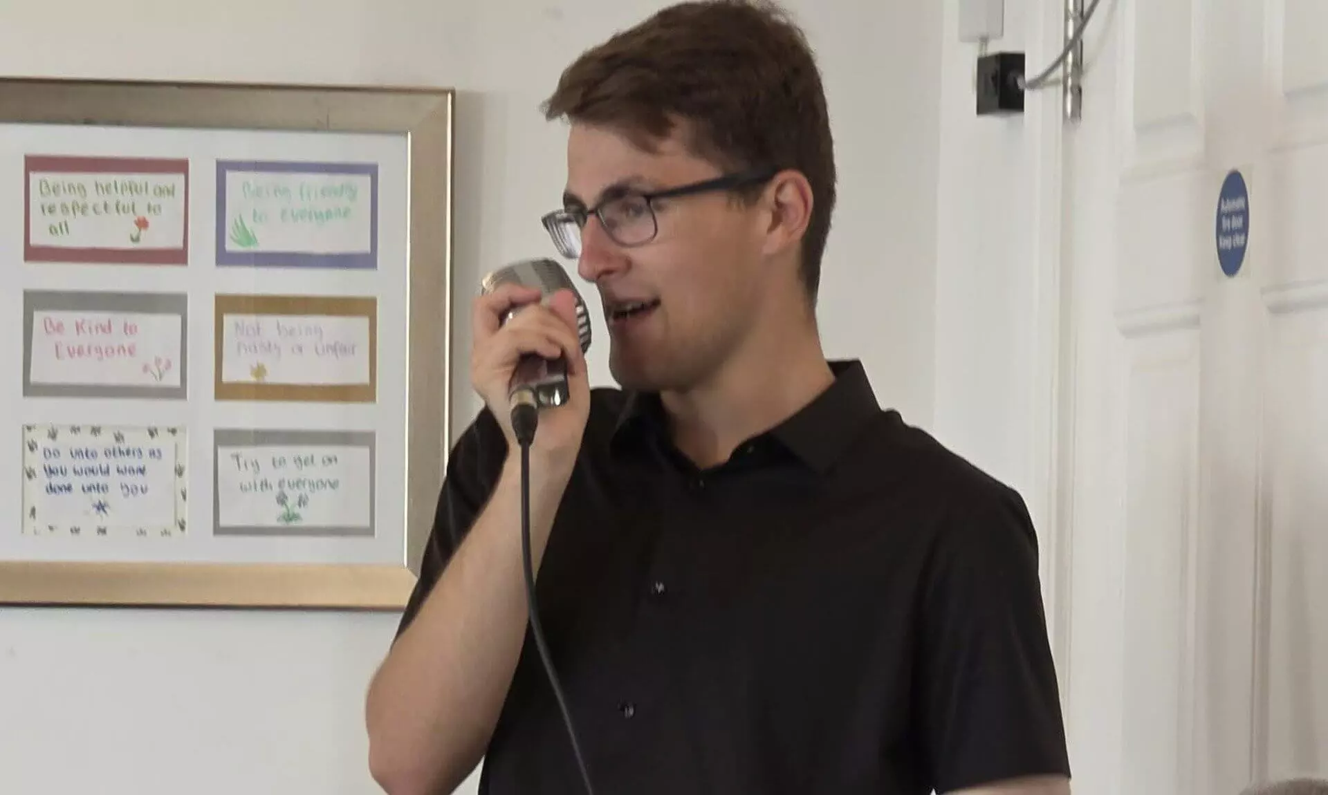Jacob Reed singing into a vintage microphone at a care home