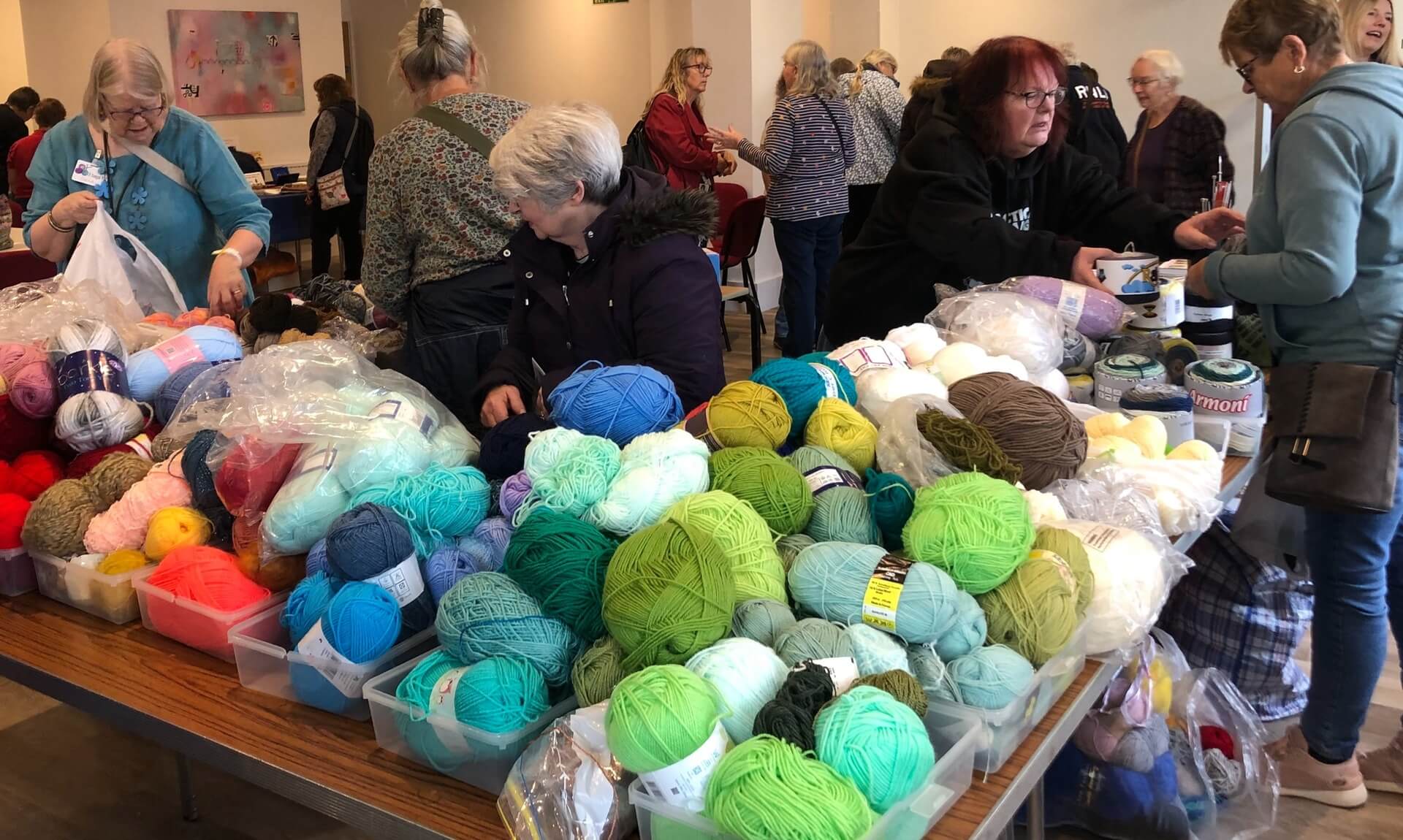 Shoppers browsing tables piled with yarn at the Liskeard Yarn Swap