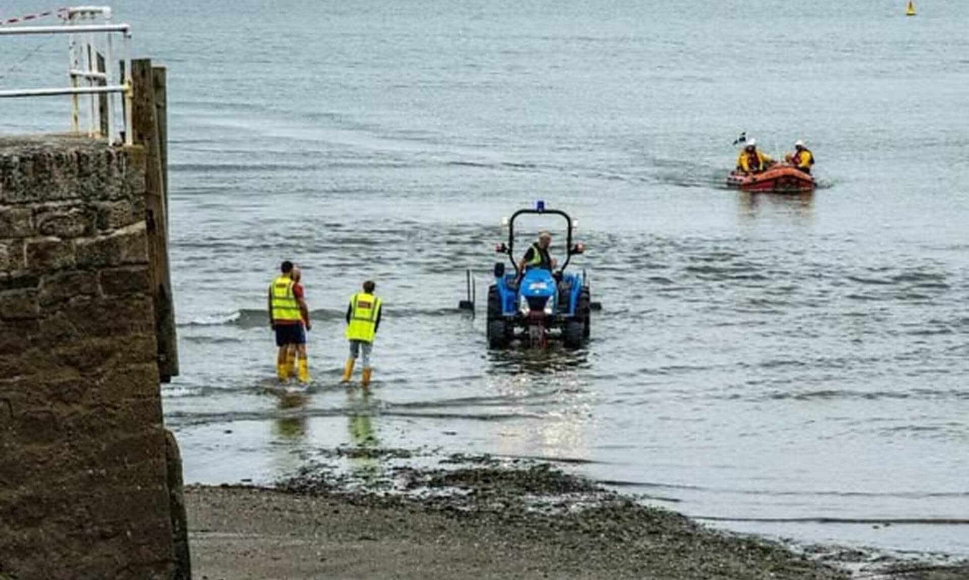 Tractor towing Looe RNLI's D Class lifeboat into the water at low tide