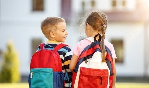 Two children walking to school wearing backpacks