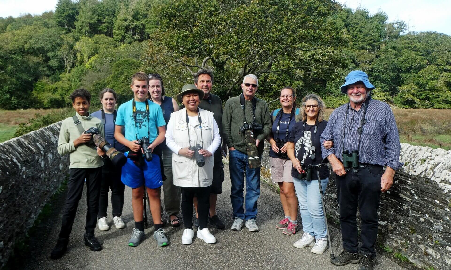 Birdwatching group with cameras and binoculars on a stone bridge at Ruan Lanihorne