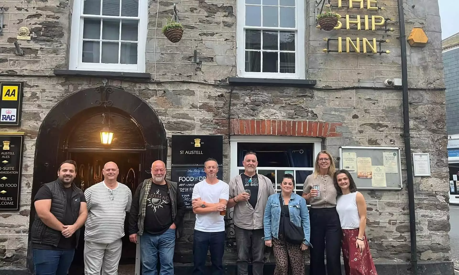 Group of villagers outside The Ship Inn in Mevagissey after helping clean up vandalism
