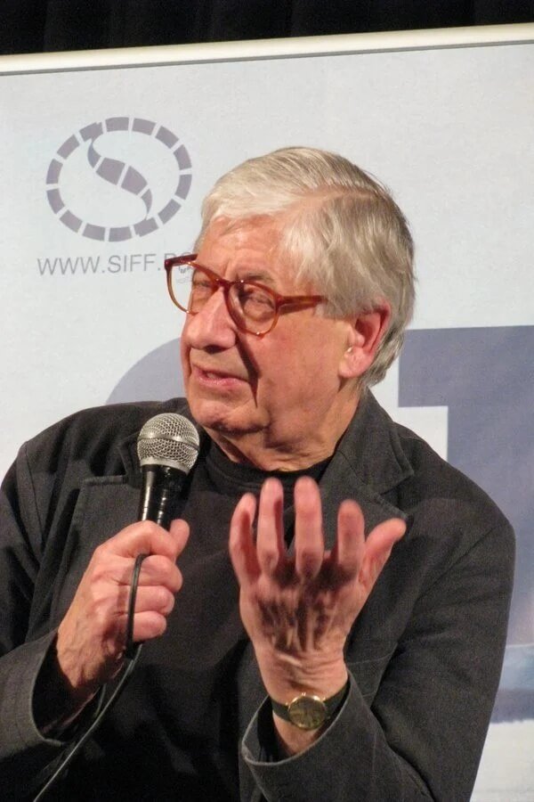 Tony Palmer speaking on stage holding a microphone