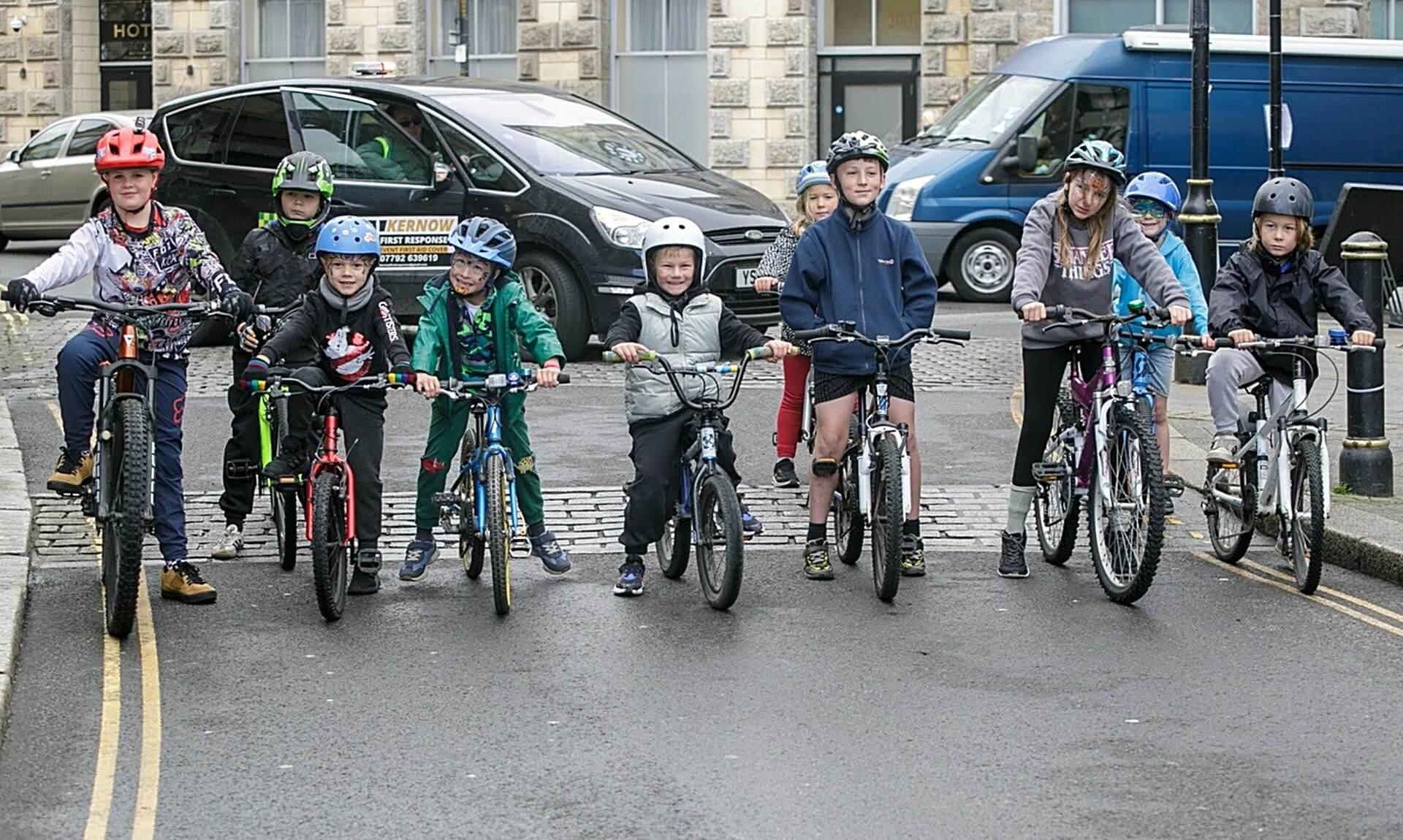 Children lined up on bikes and BMXs on a Camborne street for Tykes on Trikes