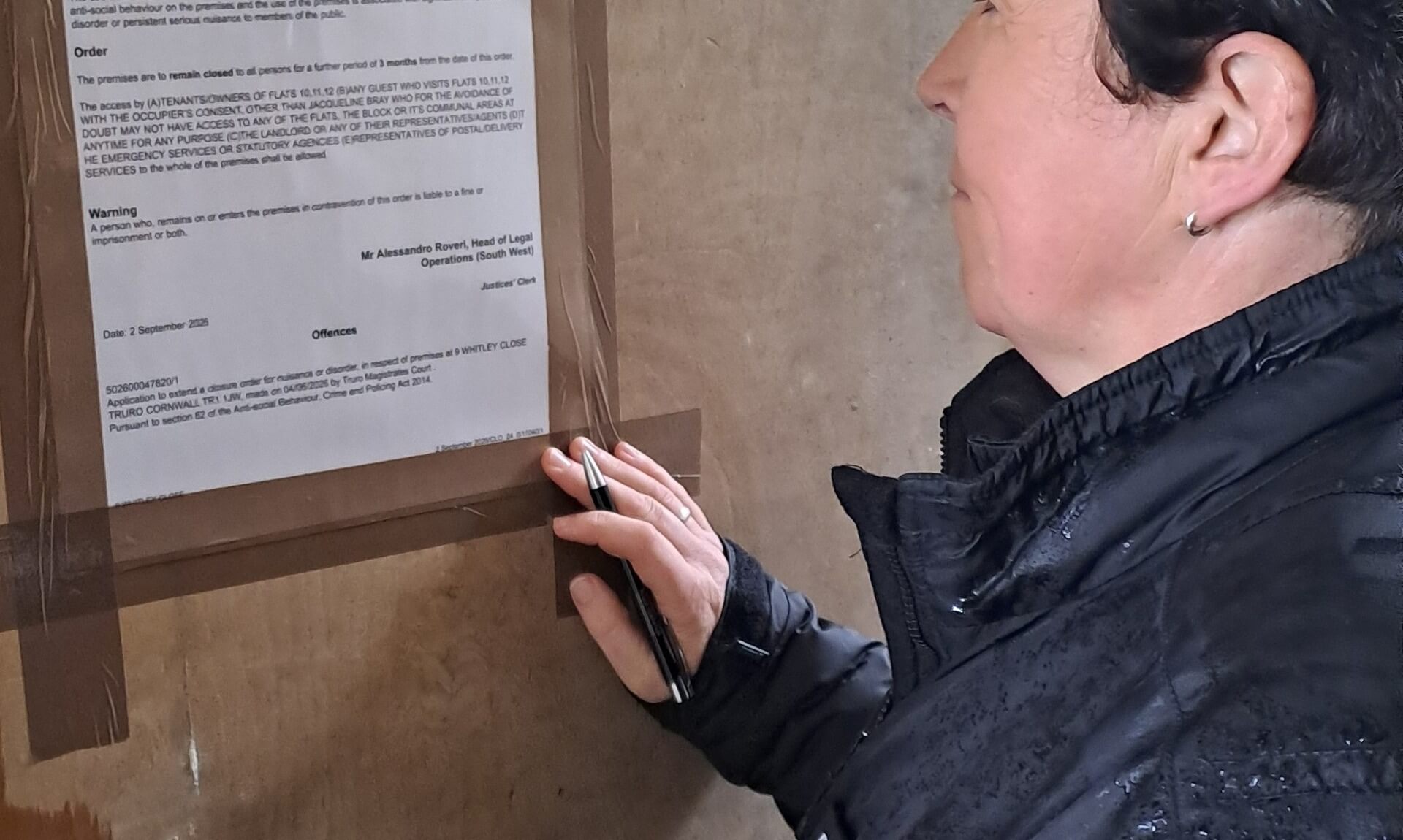 Devon and Cornwall Police officer taping a closure order notice to a property in Whitley Close, Truro