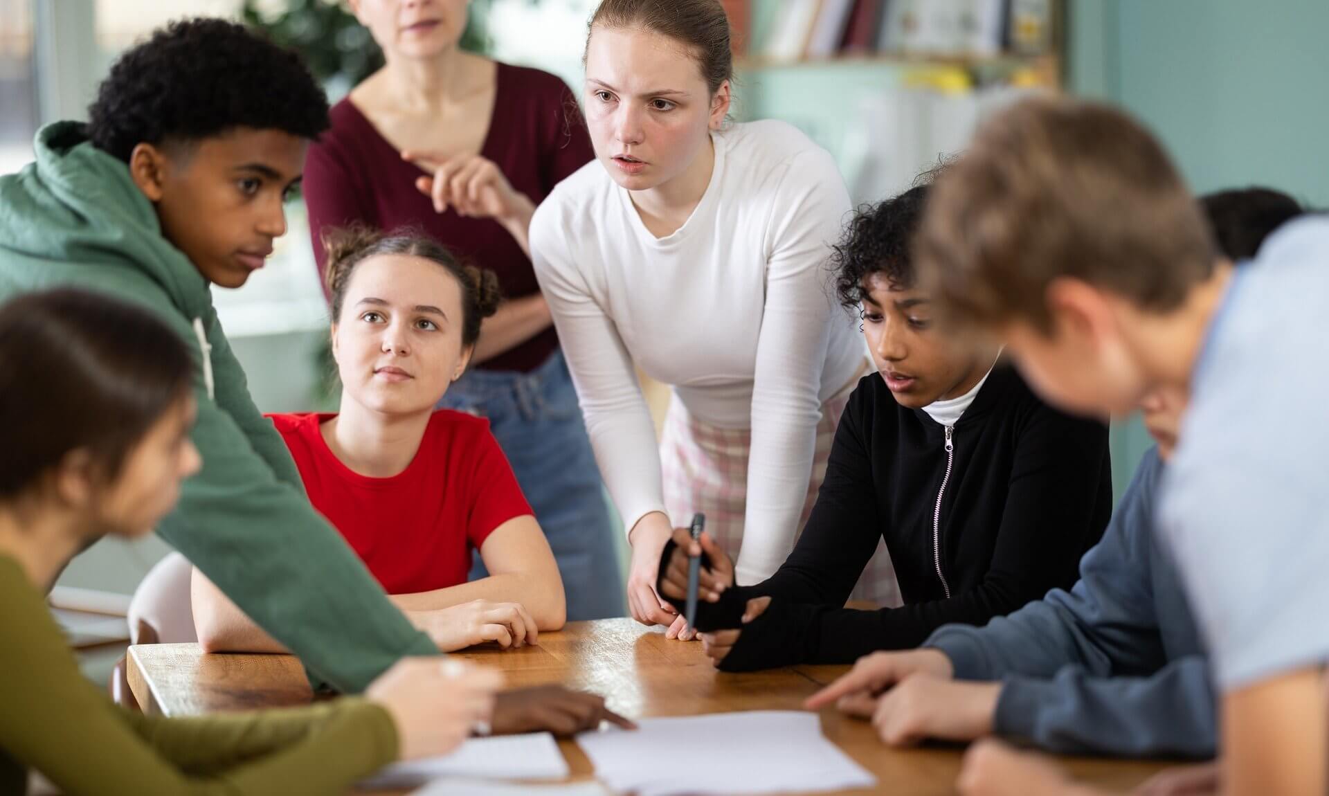 Group of young people talking around a table with a youth worker