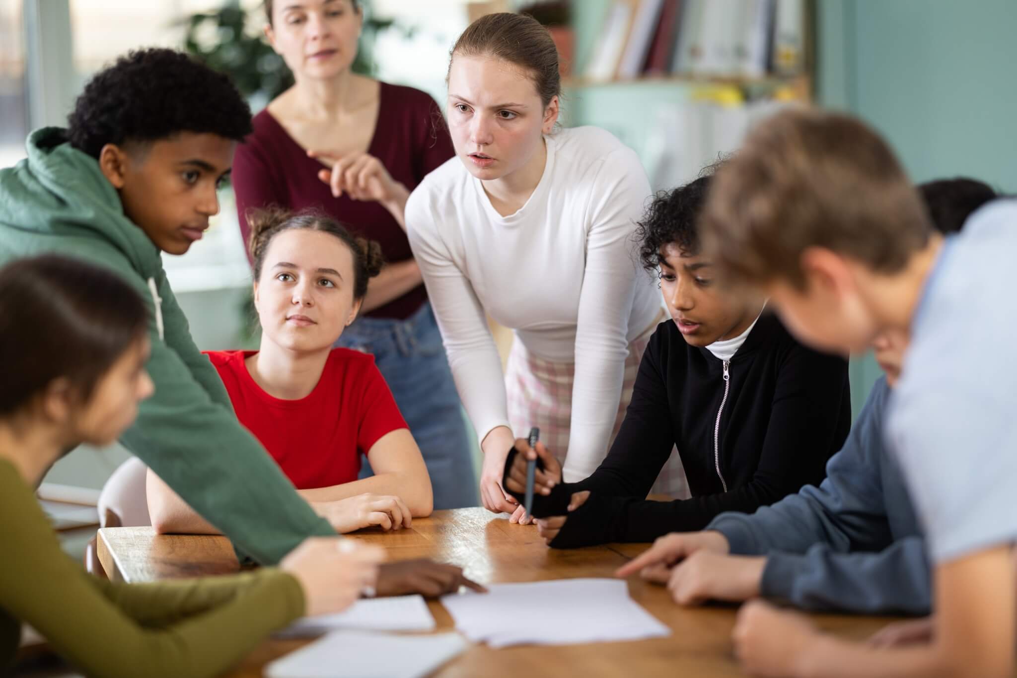 Group of young people talking around a table with a youth worker