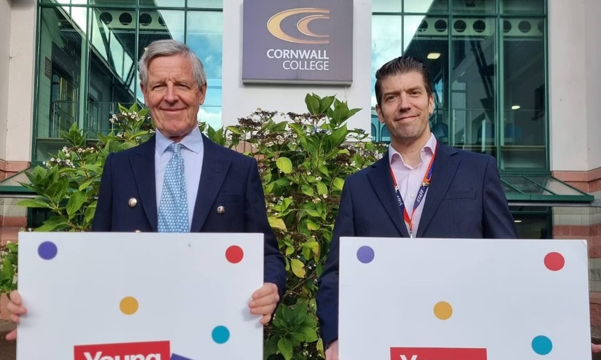Two men holding Young & Talented Cornwall signs outside Cornwall College