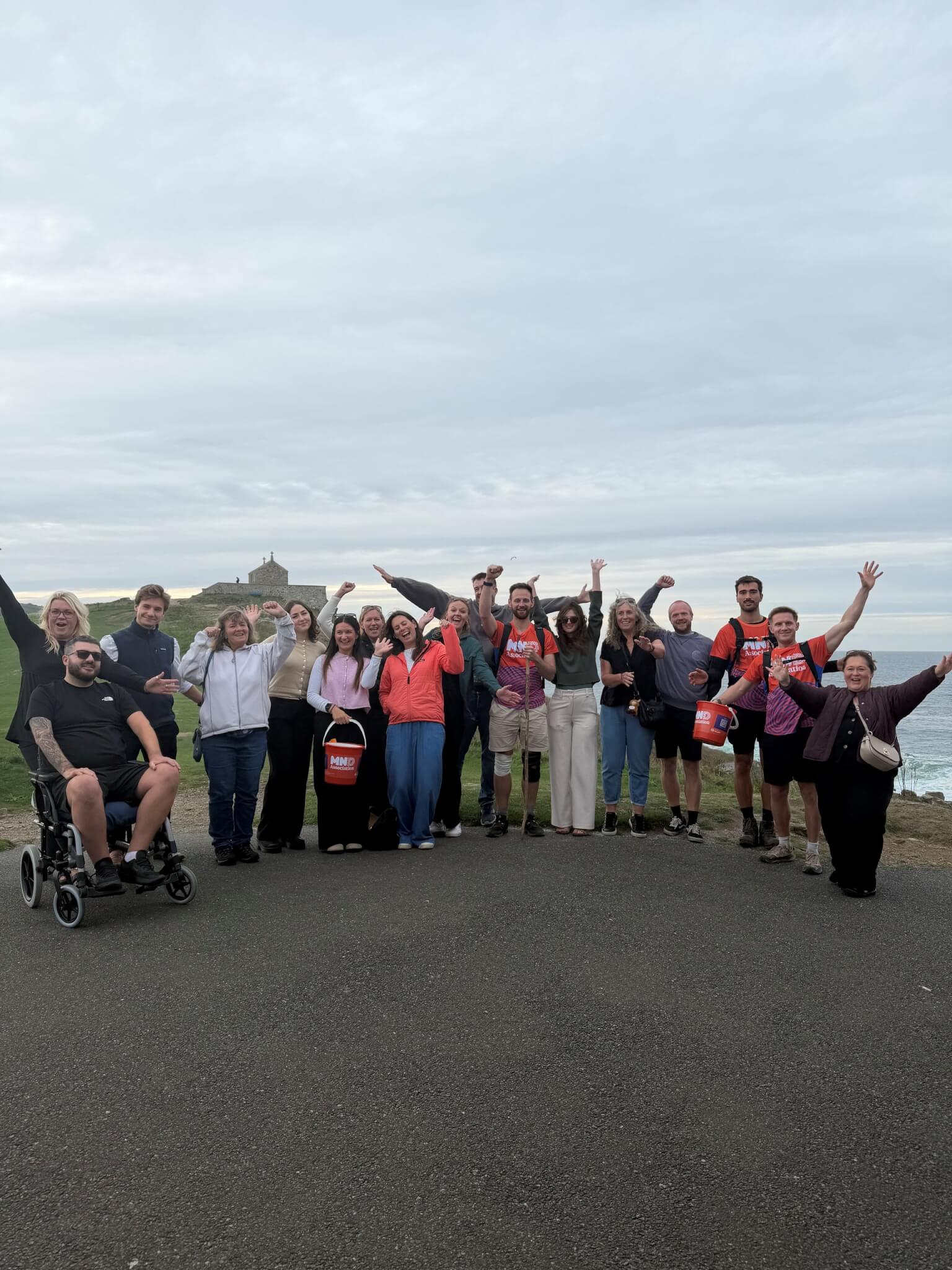 Walkers and supporters cheering on the coast at the end of The 100 Mile Hike