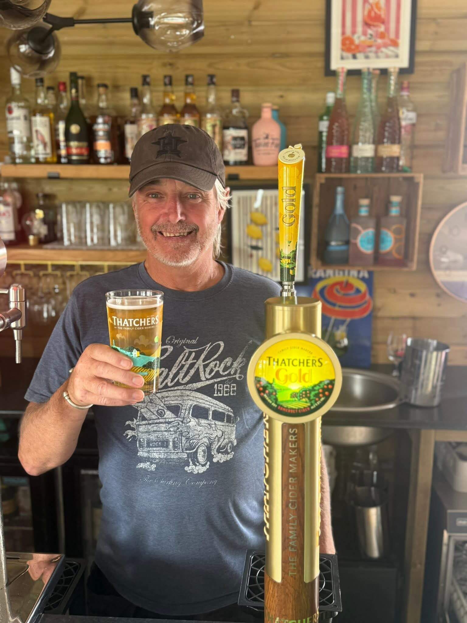 A man holding a pint of cider behind the bar