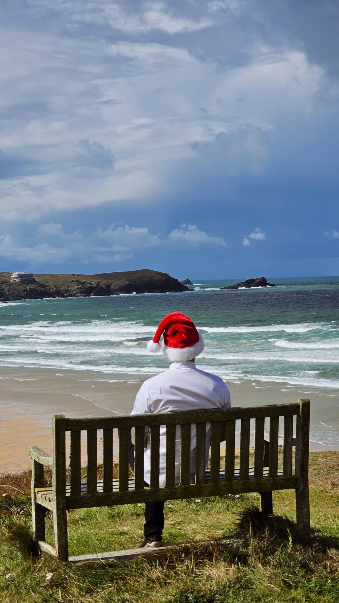 Chef in a Santa hat on a bench overlooking Fistral Beach