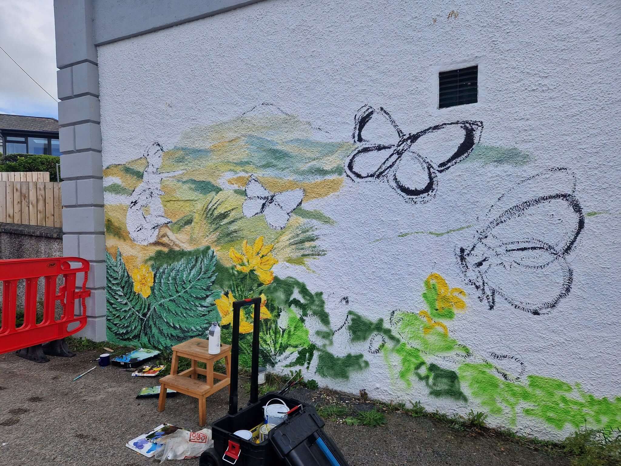 Part painted mural with butterfly outlines sketched on a white wall