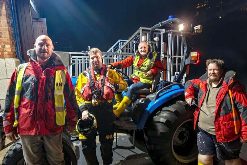 Looe RNLI volunteer crew Dave, Rich, Adam and James with a launch tractor at night