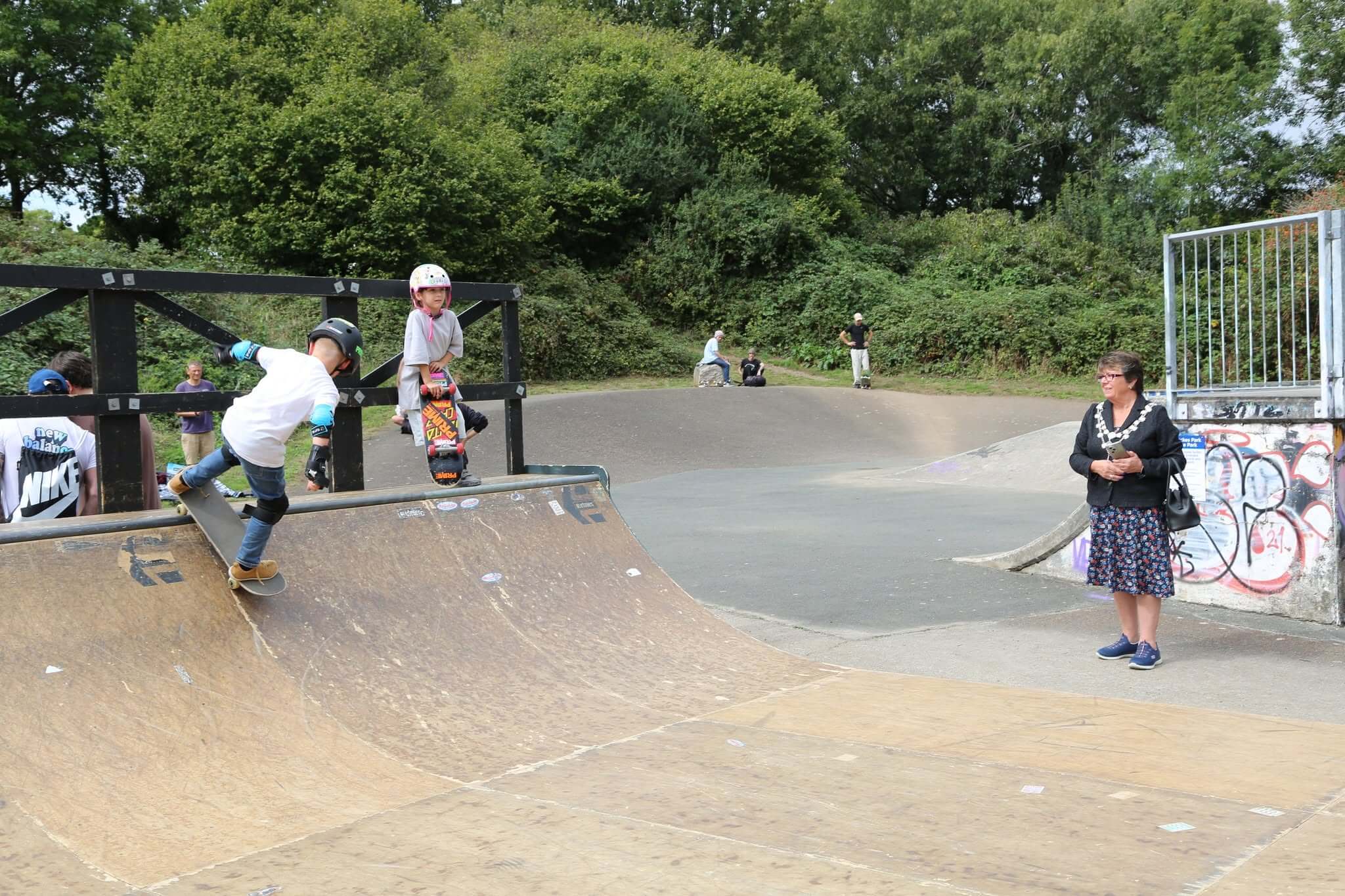 Young skaters on the mini half-pipe at Torpoint skatepark watched by the Town Mayor