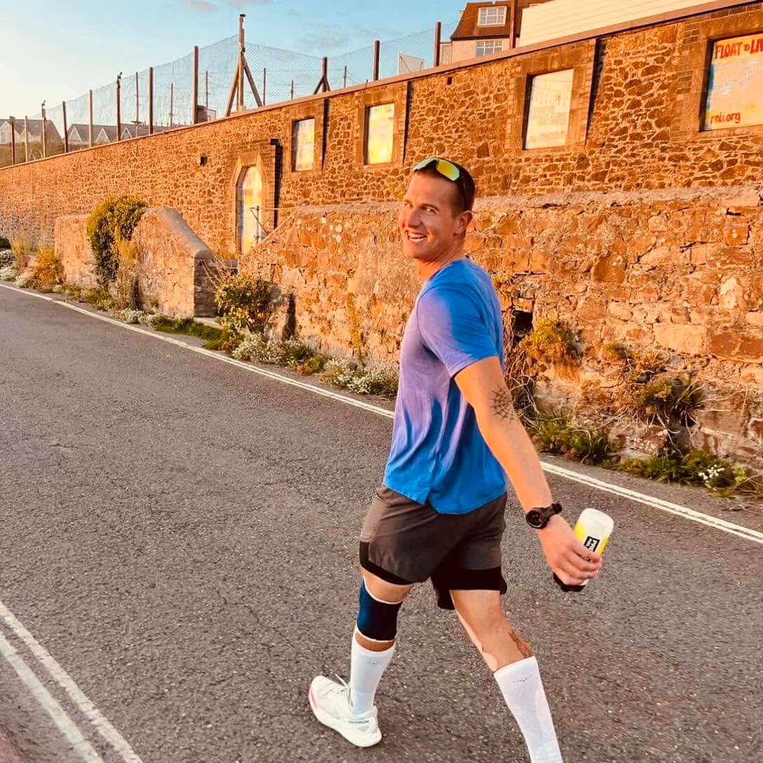 Runner in a blue t-shirt smiling during the 25-hour challenge in Bude